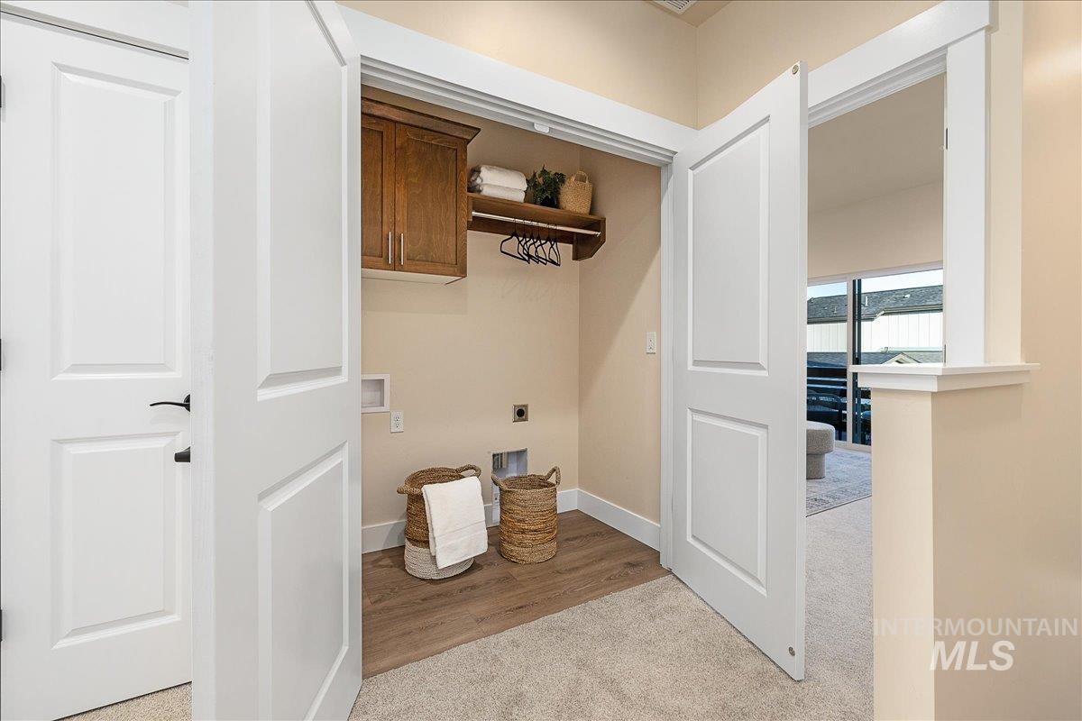 Laundry room featuring electric dryer hookup, hookup for a washing machine, light carpet, and cabinet space