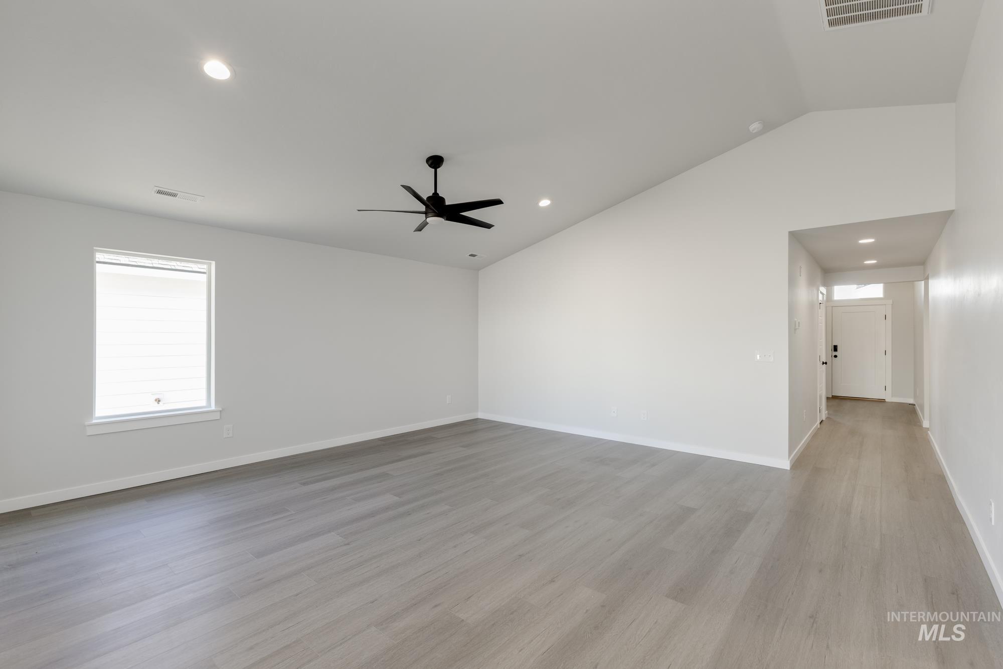 Empty room featuring vaulted ceiling, light wood-style flooring, recessed lighting, and ceiling fan