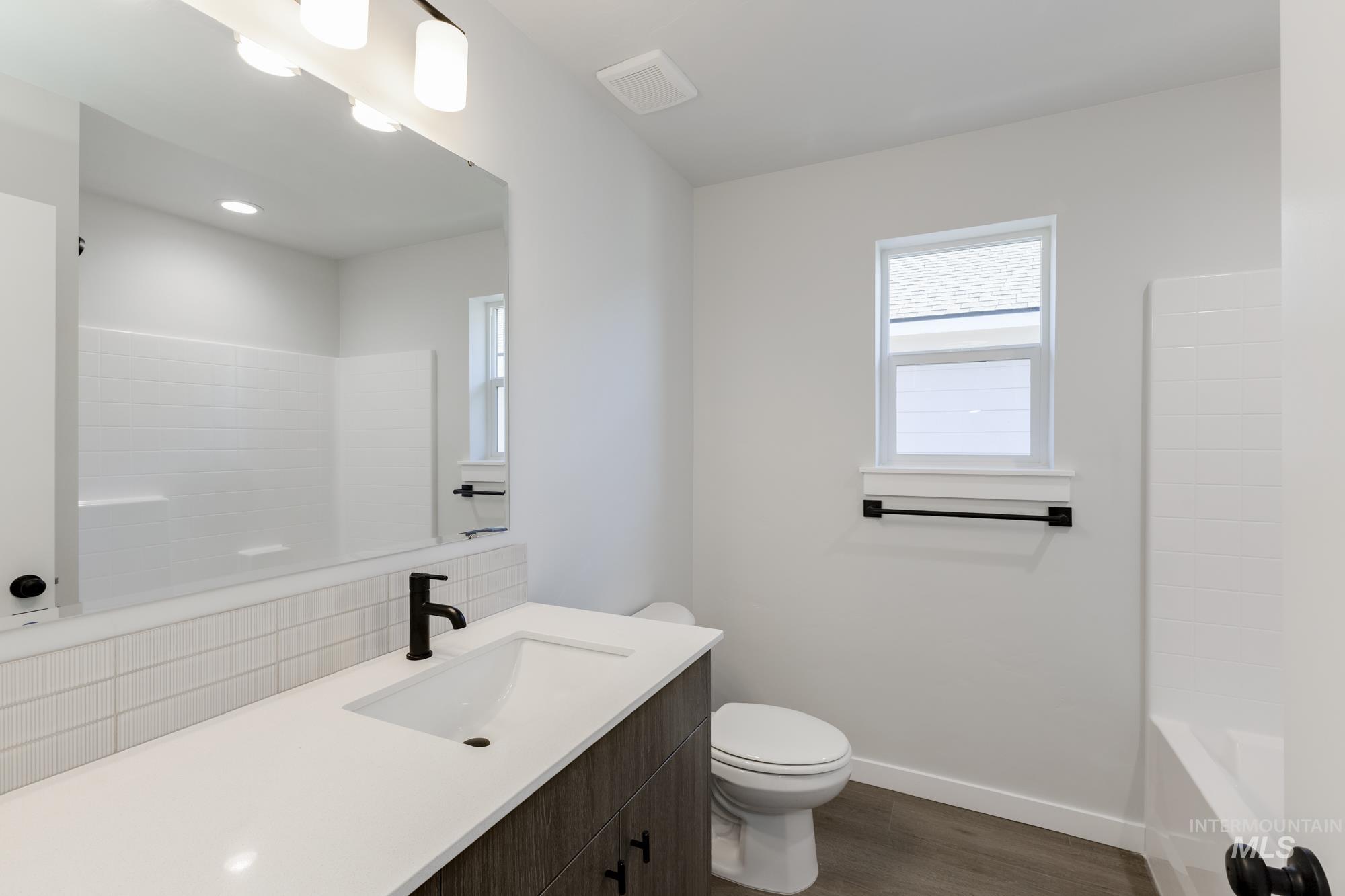 Full bathroom featuring vanity, tasteful backsplash, dark wood-style floors, and shower / bathtub combination