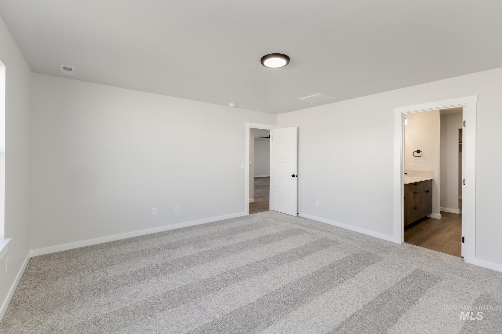 Unfurnished bedroom featuring light carpet and connected bathroom