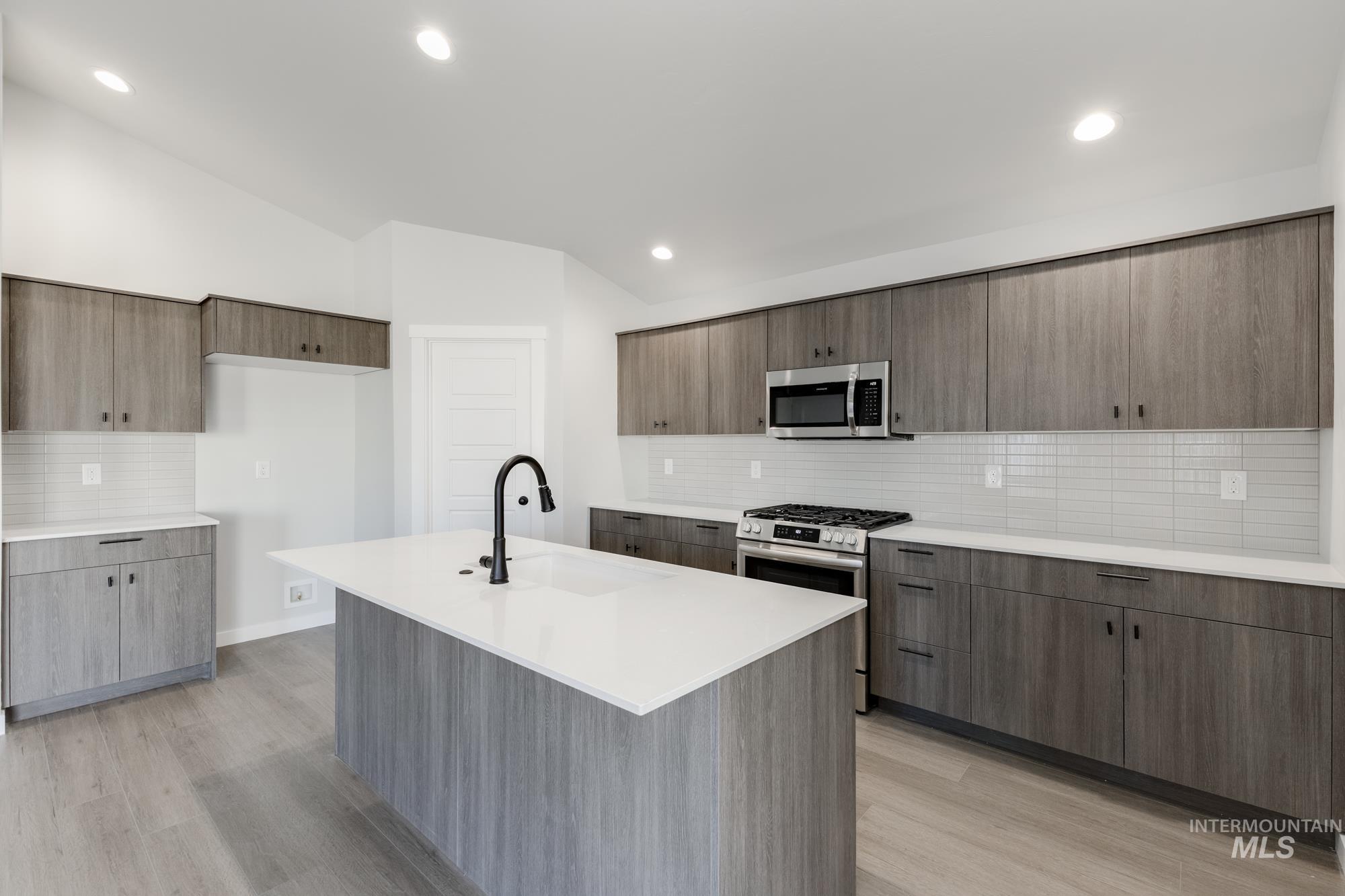 Kitchen featuring tasteful backsplash, appliances with stainless steel finishes, modern cabinets, vaulted ceiling, and recessed lighting