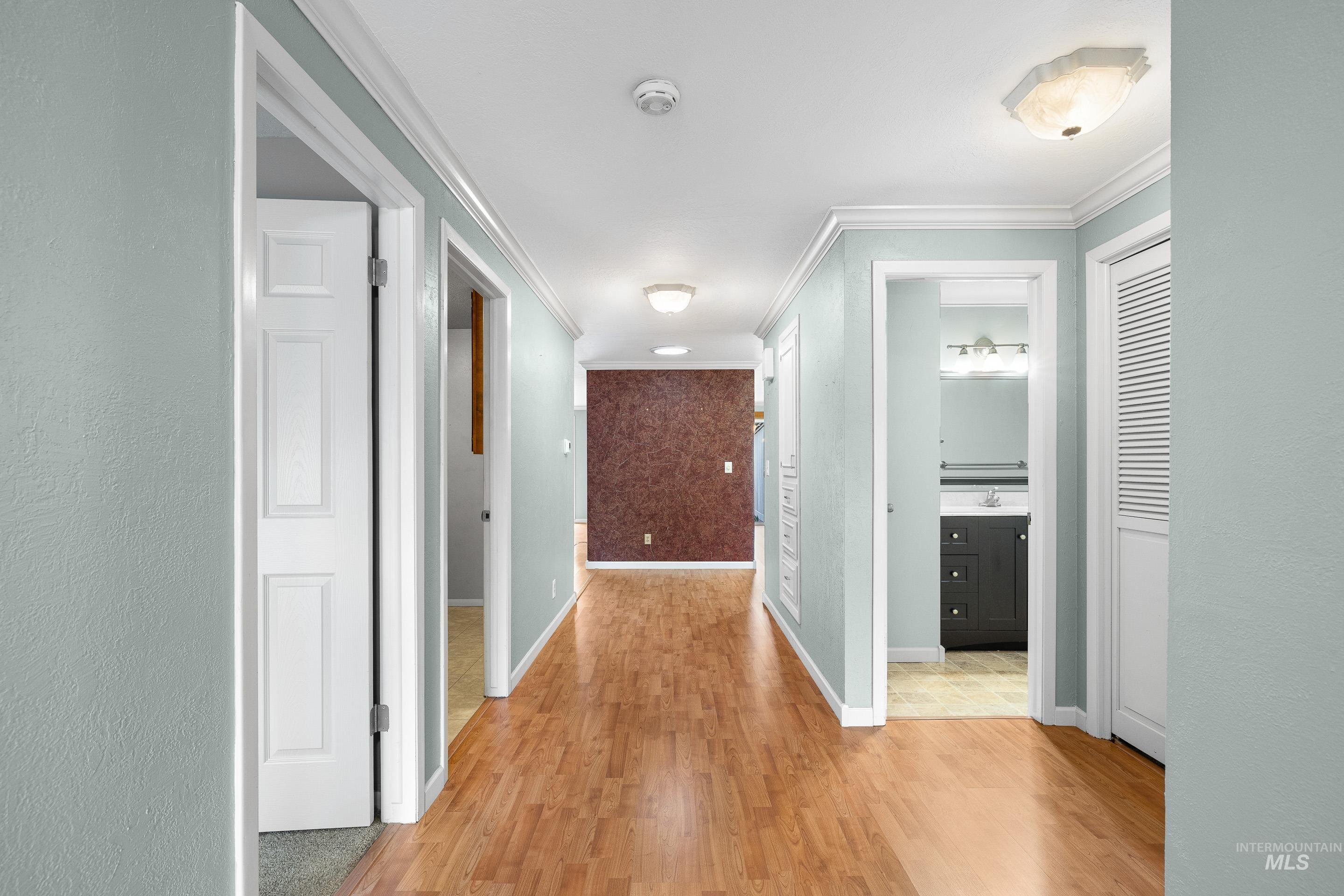 Corridor featuring light wood-style flooring and crown molding