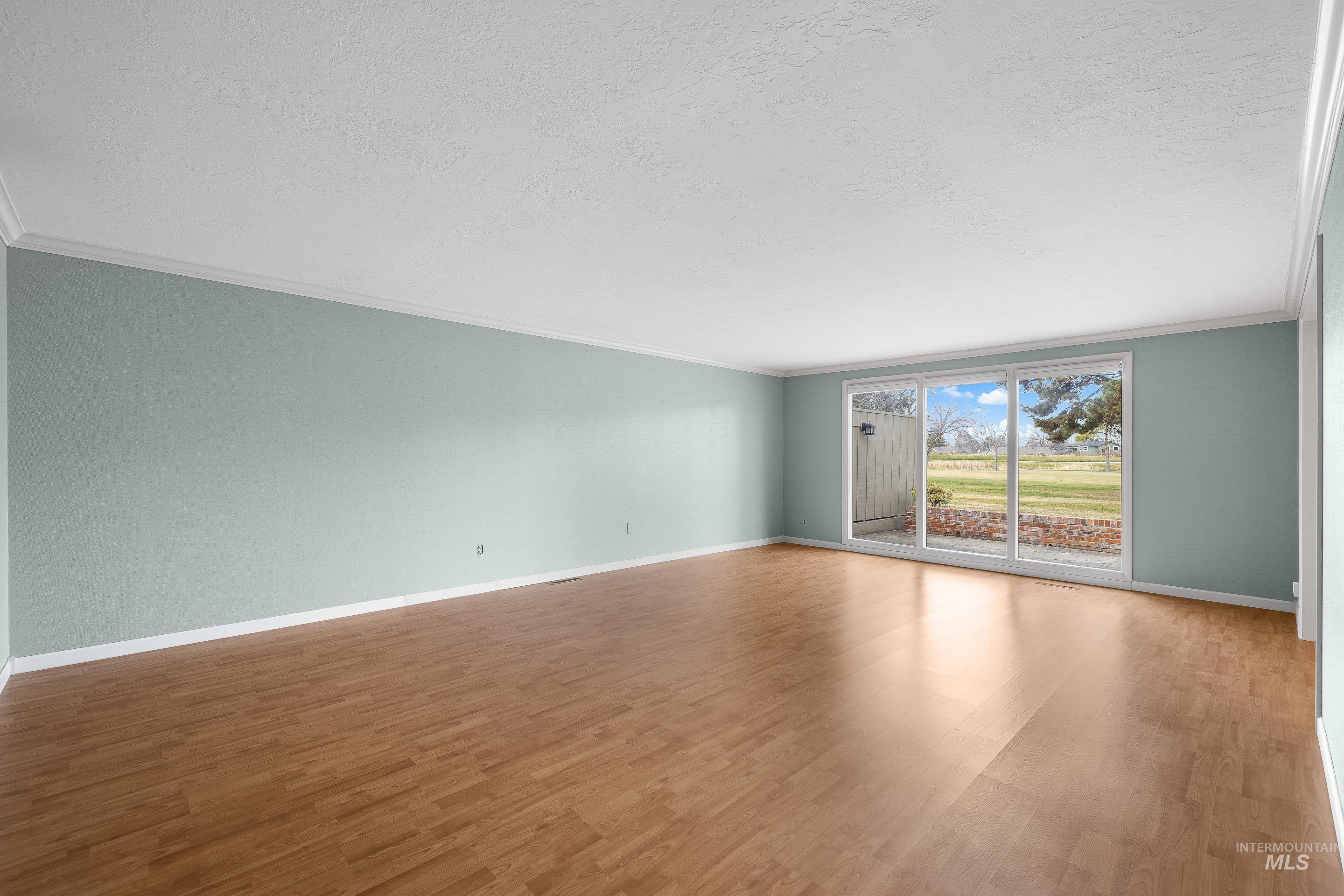 Unfurnished room with crown molding, wood finished floors, and a textured ceiling