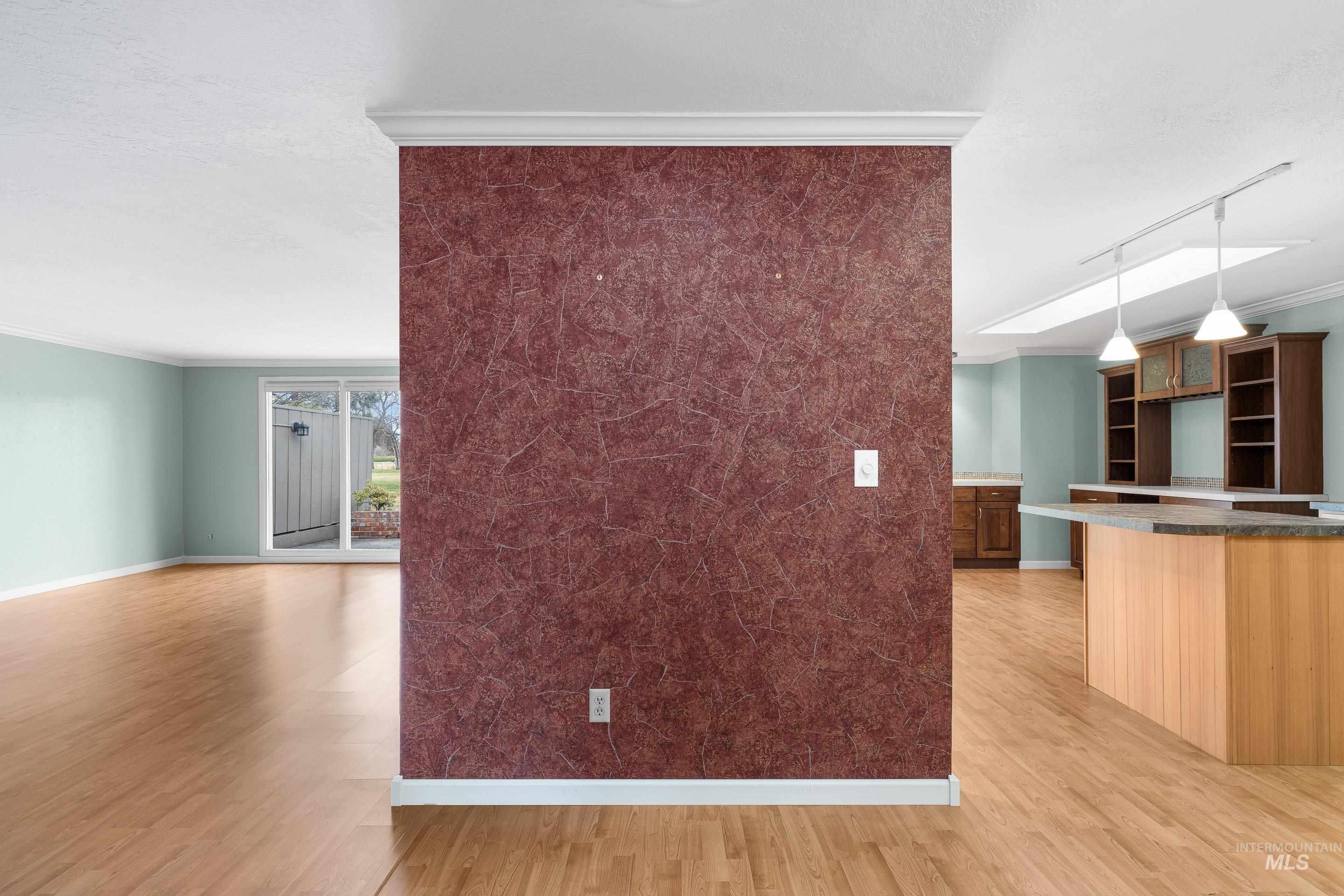 Kitchen with ornamental molding, light wood finished floors, rail lighting, and dark stone countertops