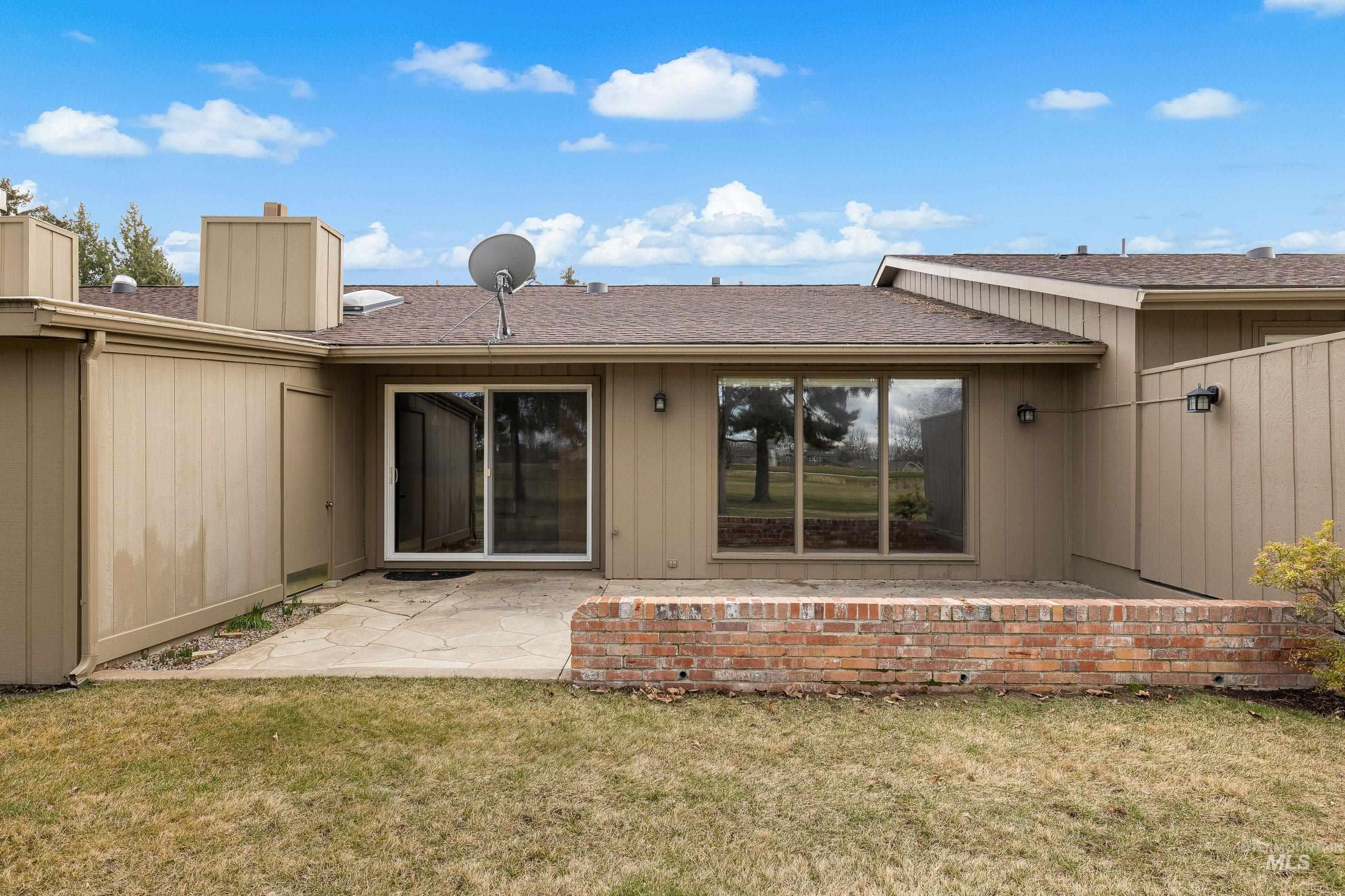 Back of property featuring a chimney, a shingled roof, a patio, and a lawn