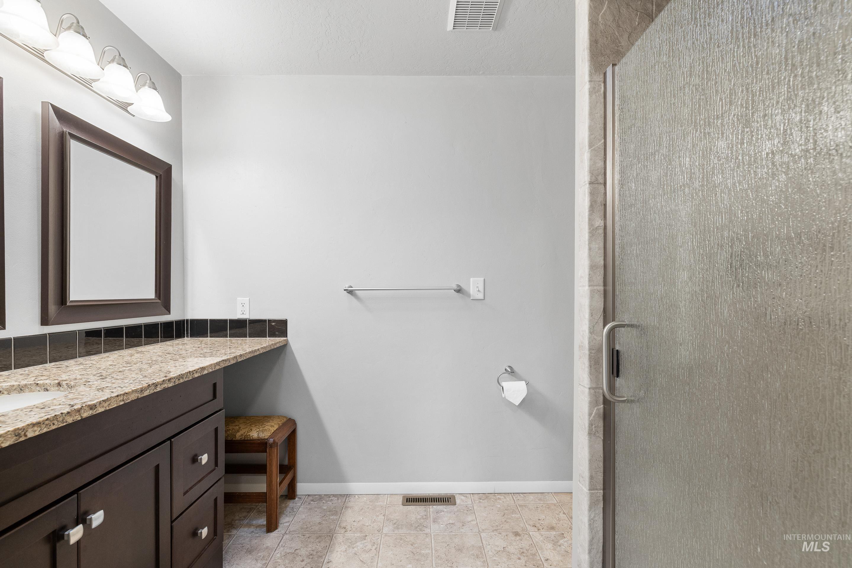 Bathroom with vanity, a stall shower, and light tile patterned floors
