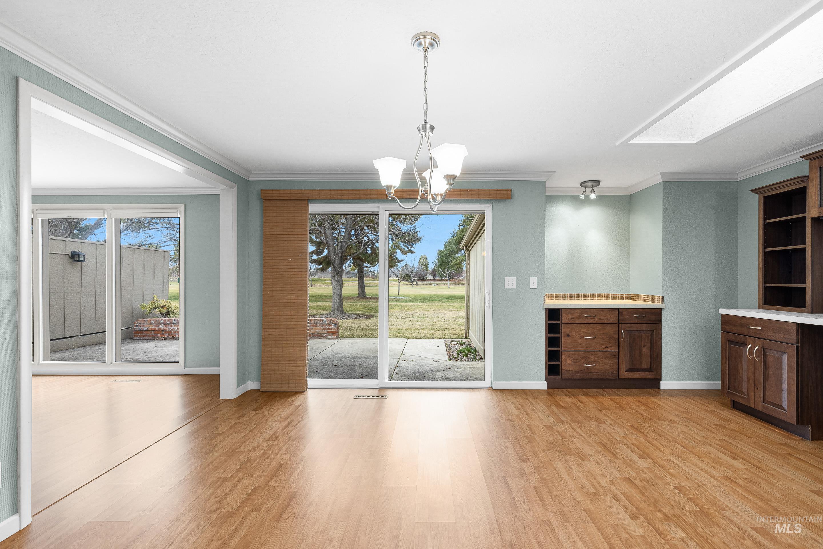 Unfurnished dining area with a chandelier, crown molding, and light wood finished floors