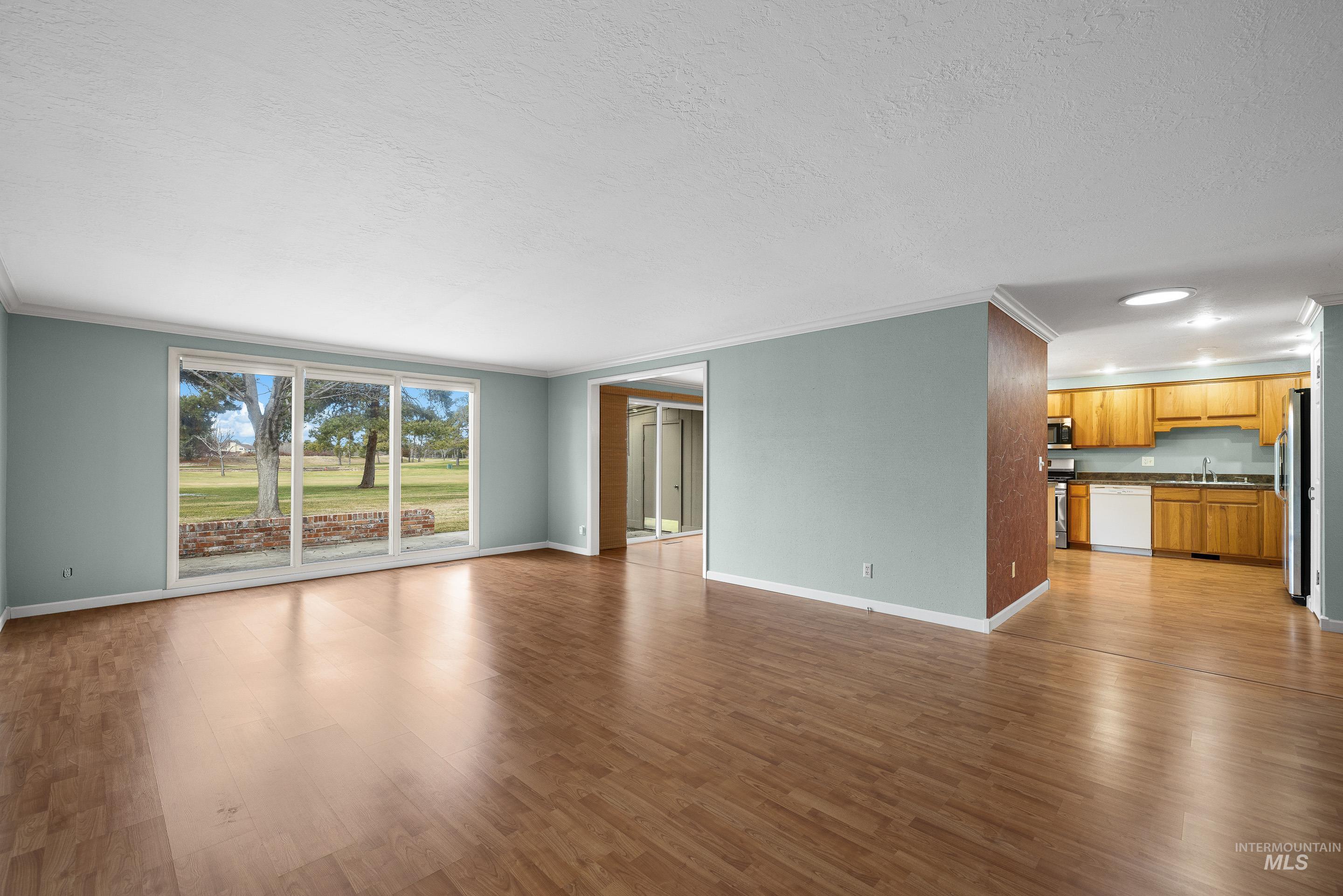 Unfurnished living room with dark wood finished floors, crown molding, a textured ceiling, and recessed lighting