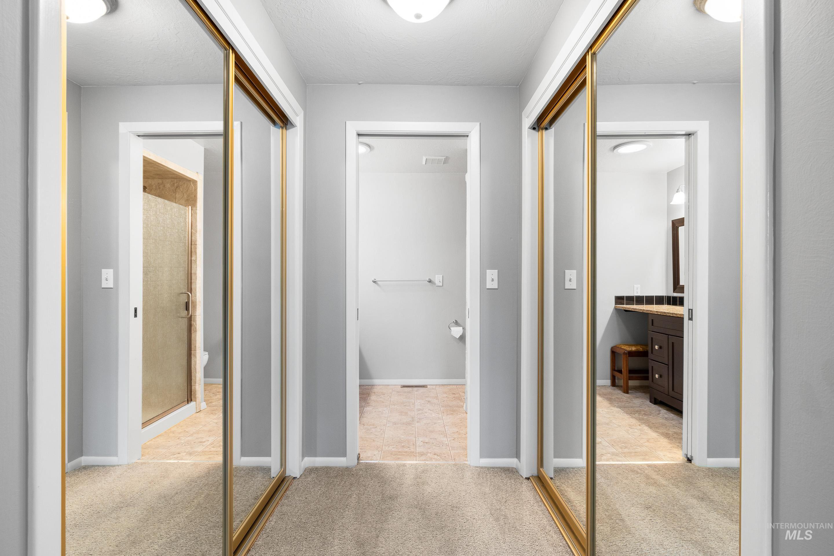Corridor featuring light colored carpet and baseboards