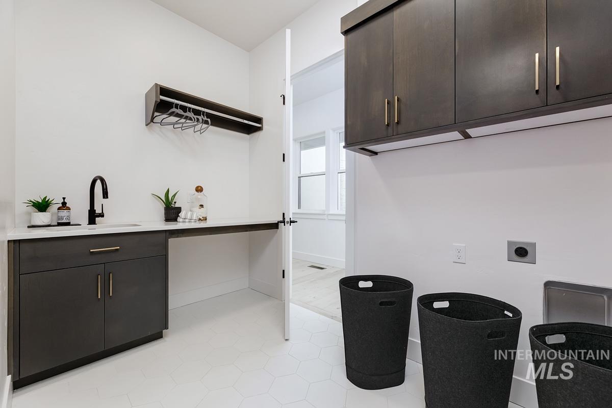 Laundry room with hookup for an electric dryer, cabinet space, and light tile patterned floors