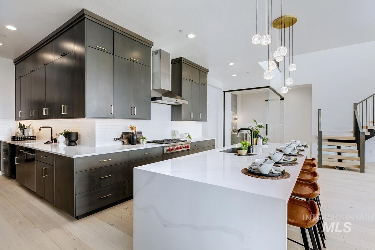 Kitchen with pendant lighting, light wood-style floors, a breakfast bar area, decorative backsplash, and a large island