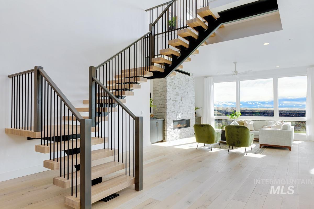 Stairway featuring wood-type flooring, a fireplace, a ceiling fan, recessed lighting, and a towering ceiling