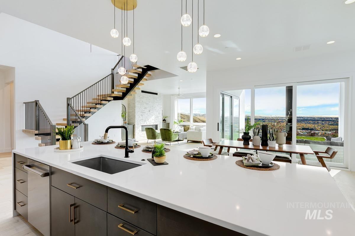 Kitchen with pendant lighting, light stone counters, open floor plan, a center island with sink, and stainless steel dishwasher