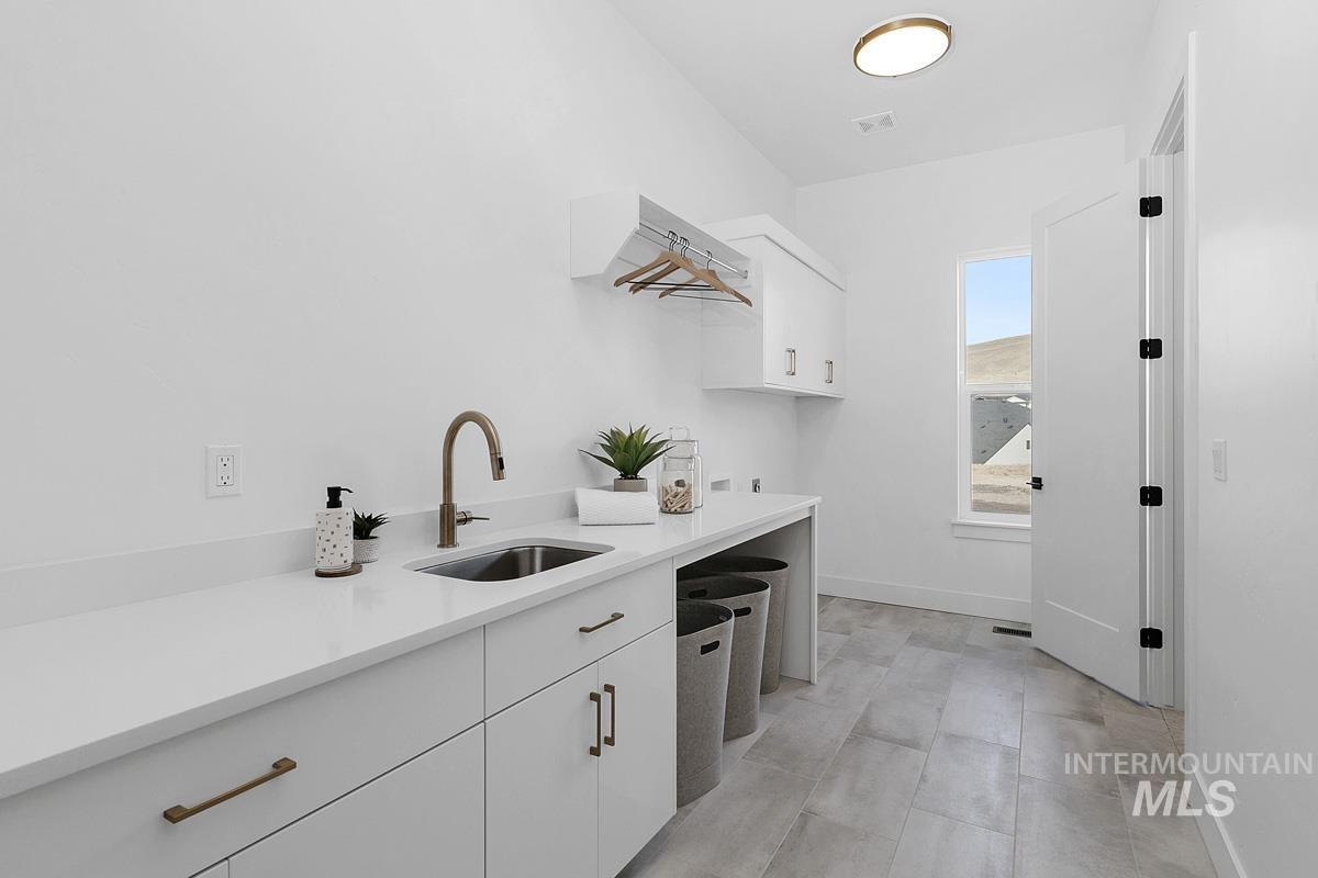 Laundry room with cabinet space and baseboards