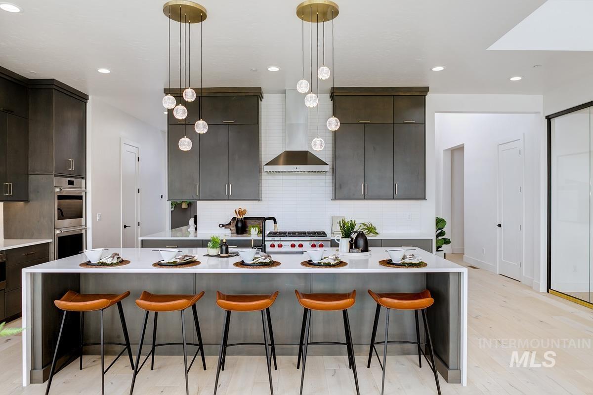 Kitchen featuring a breakfast bar, hanging light fixtures, tasteful backsplash, a large island, and light stone counters