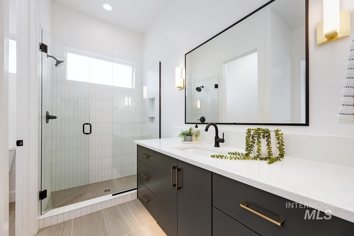 Bathroom featuring vanity, a shower stall, light tile patterned floors, and recessed lighting