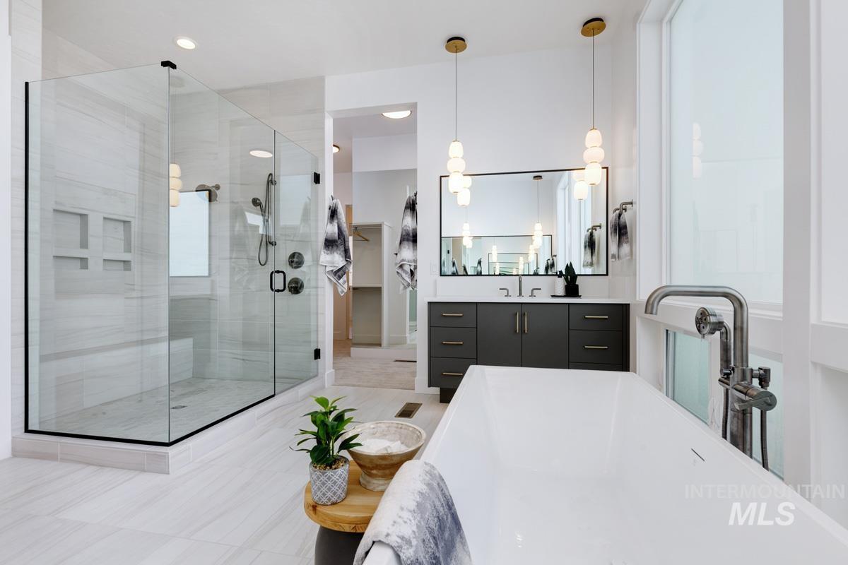 Full bath featuring vanity, a freestanding tub, a shower stall, and light tile patterned flooring