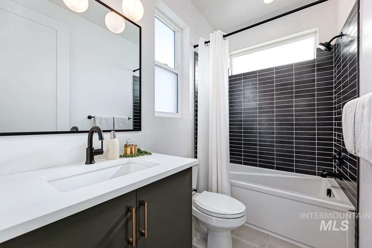 Full bath with shower / bath combo with shower curtain, vanity, and light tile patterned floors