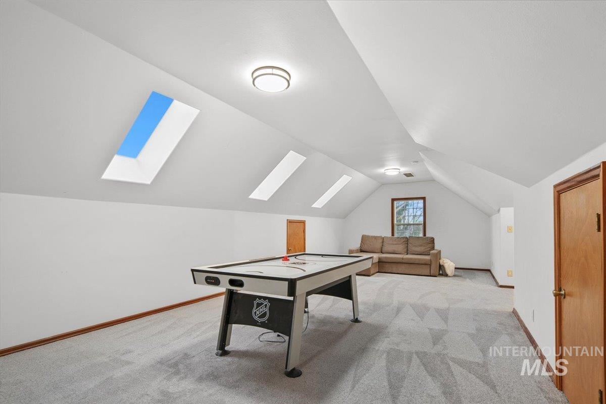 Game room featuring light colored carpet, lofted ceiling, and a skylight