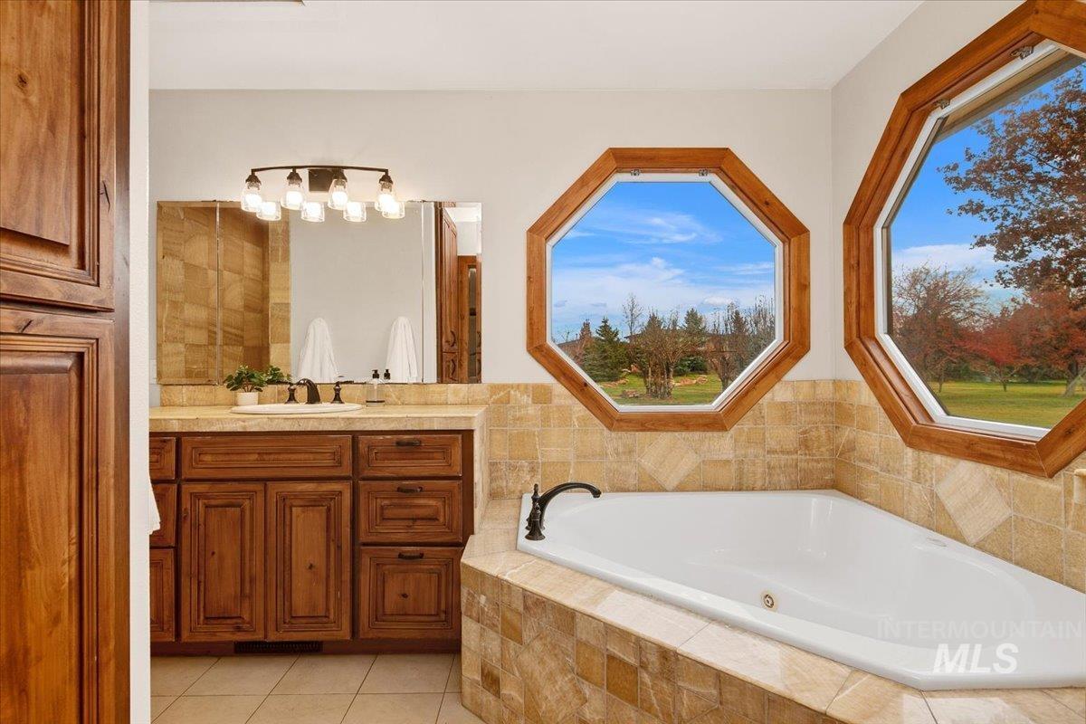 Bathroom featuring a garden tub, vanity, and light tile patterned floors
