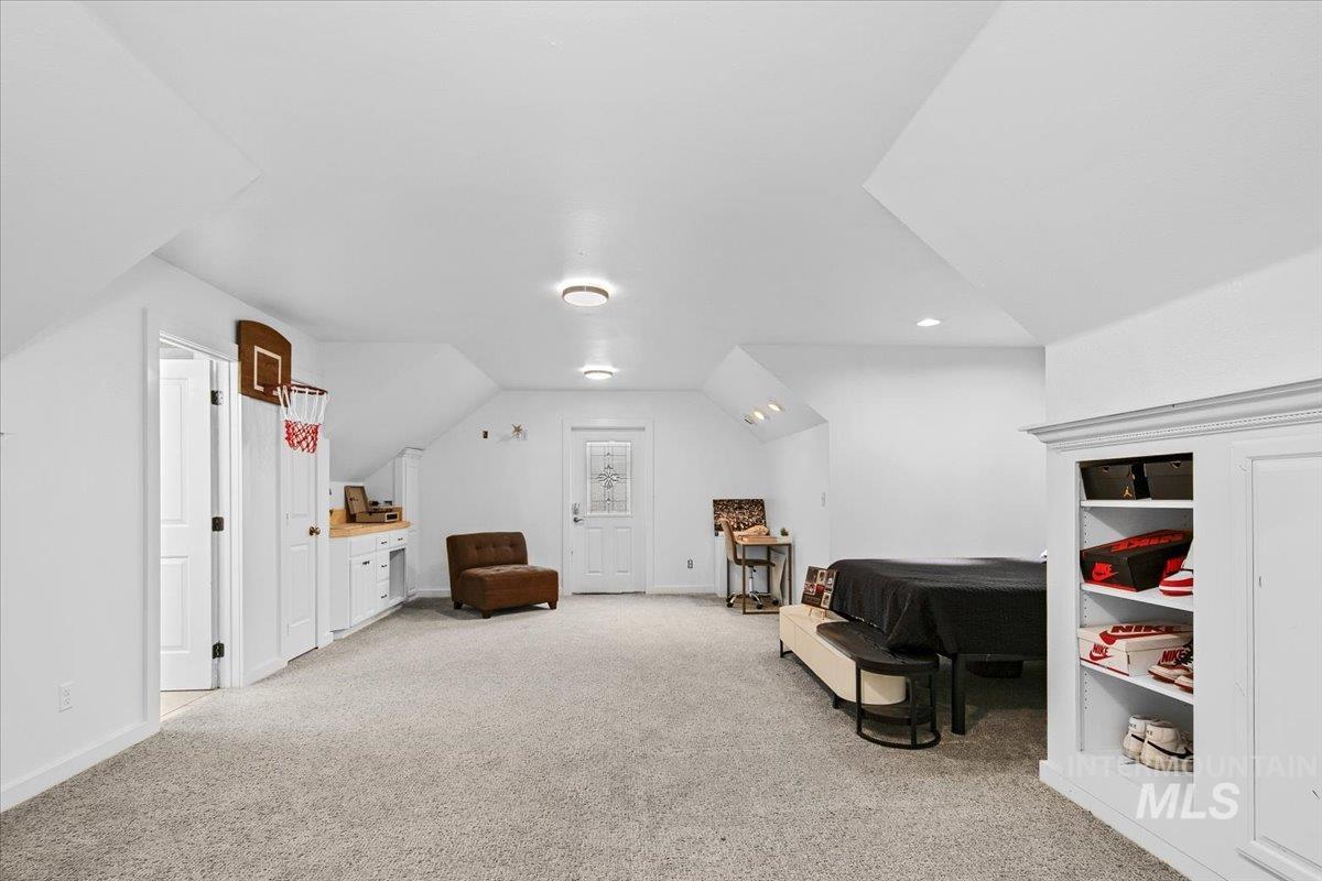 Bedroom with vaulted ceiling and light carpet
