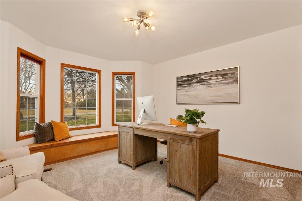 Home office with light carpet and a chandelier