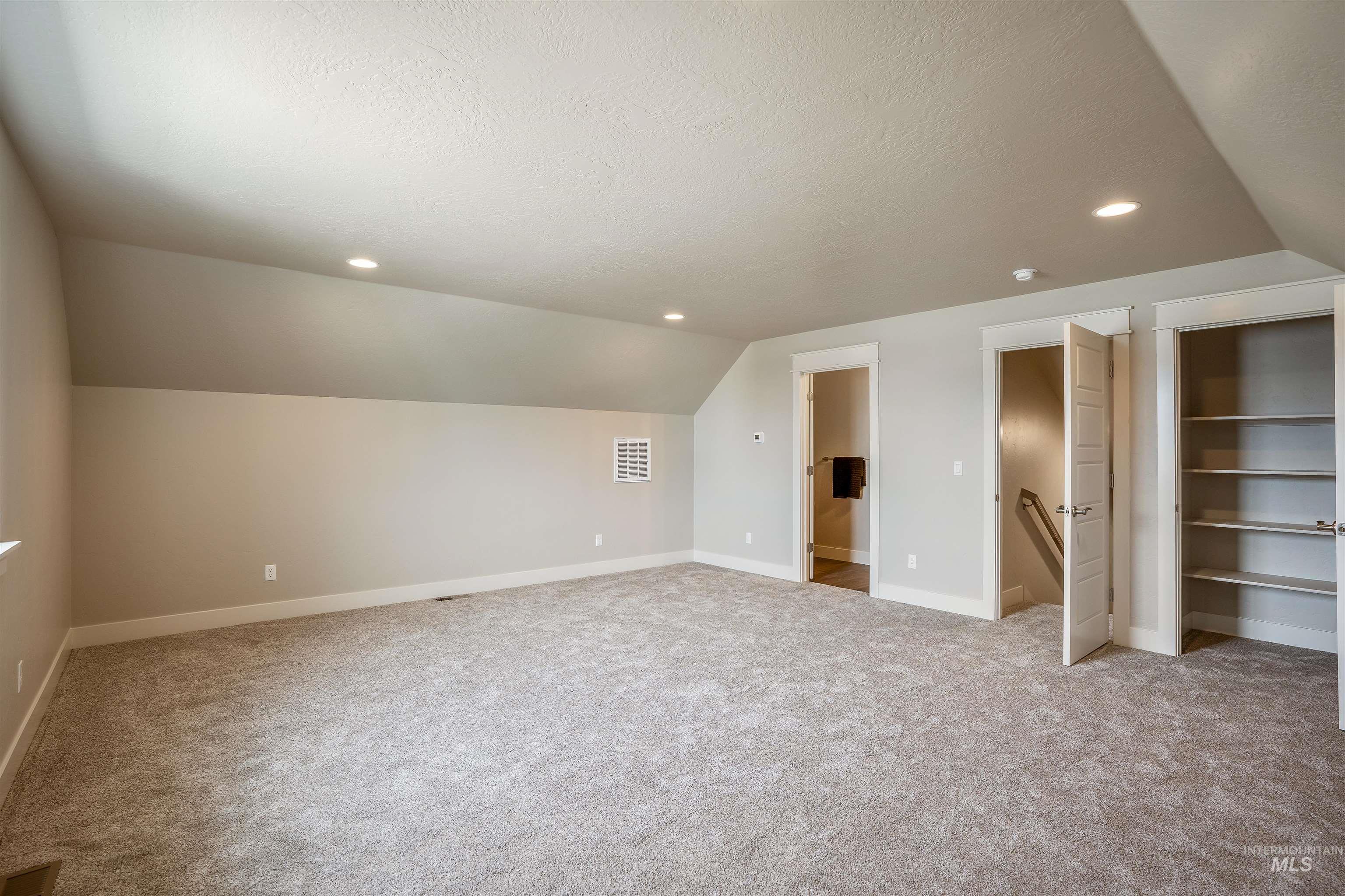 Additional living space featuring a textured ceiling, lofted ceiling, recessed lighting, and light colored carpet