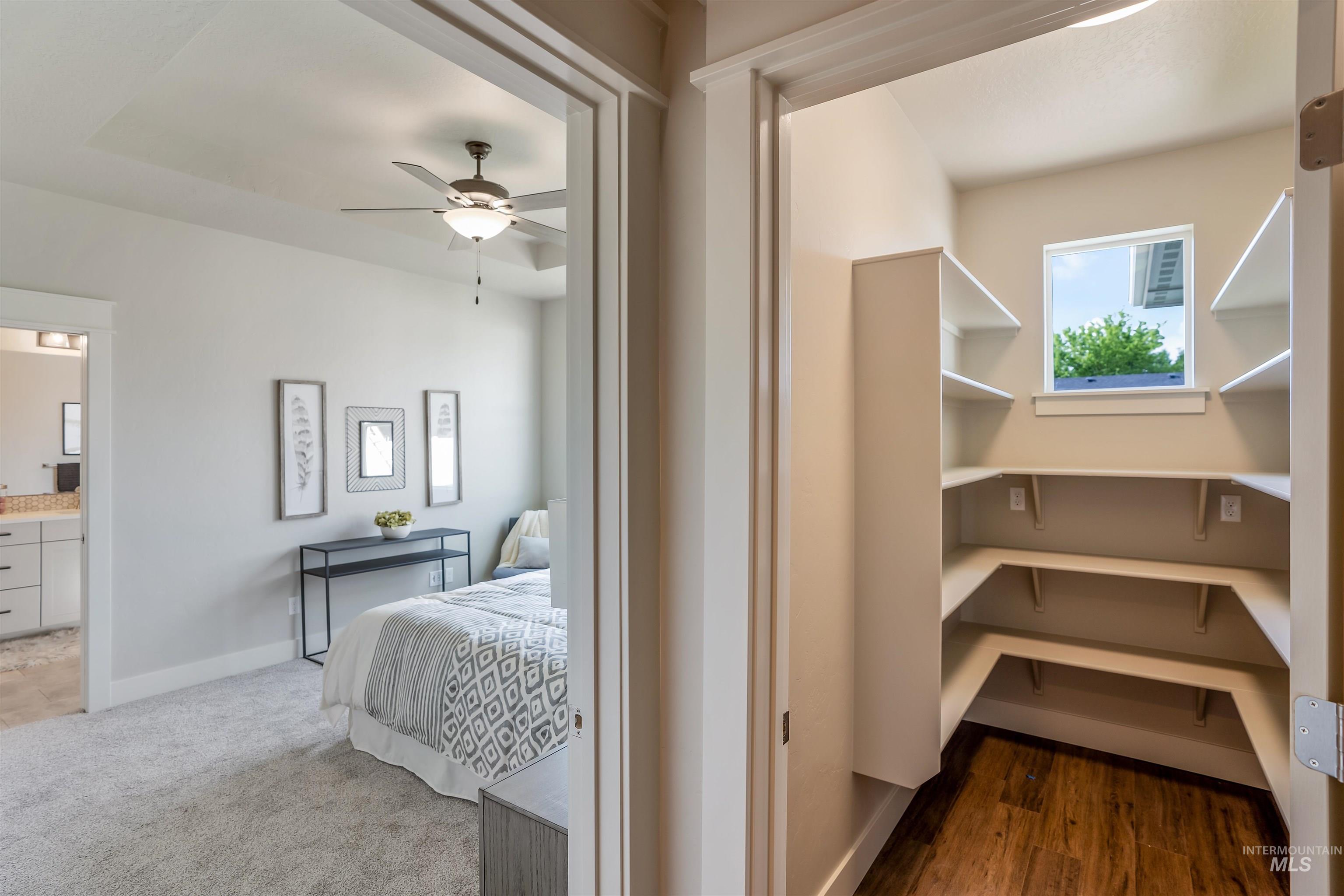 Bedroom with a ceiling fan, ensuite bath, and dark colored carpet