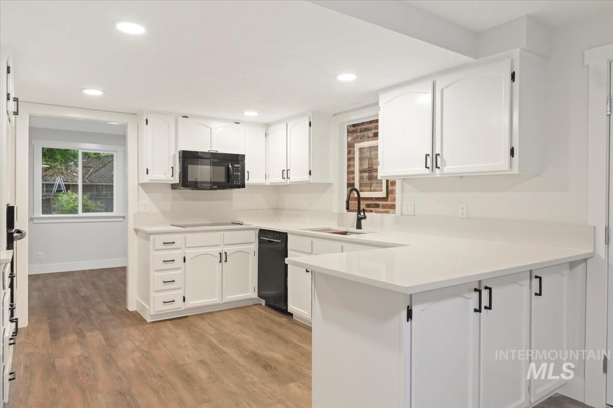 Kitchen with white cabinets, a peninsula, light wood finished floors, and recessed lighting