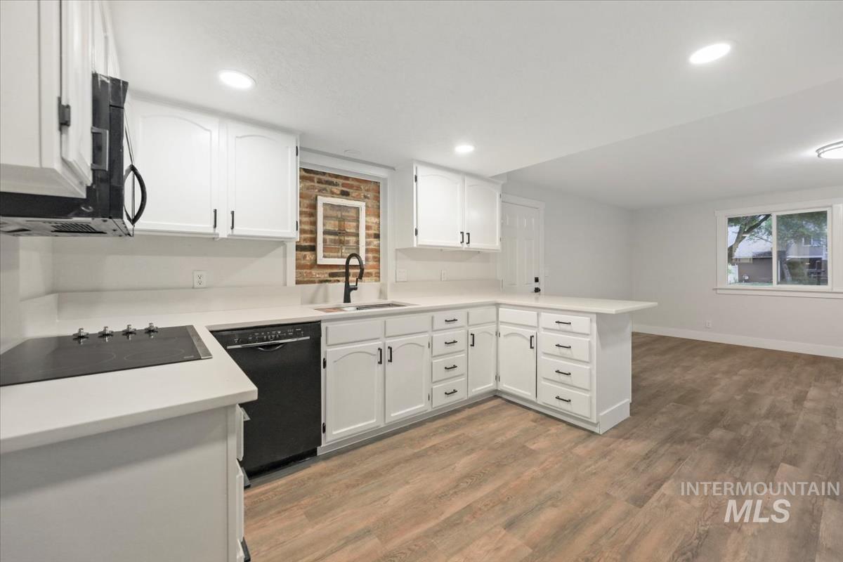 Kitchen featuring white cabinetry, a peninsula, light countertops, light wood-style floors, and recessed lighting
