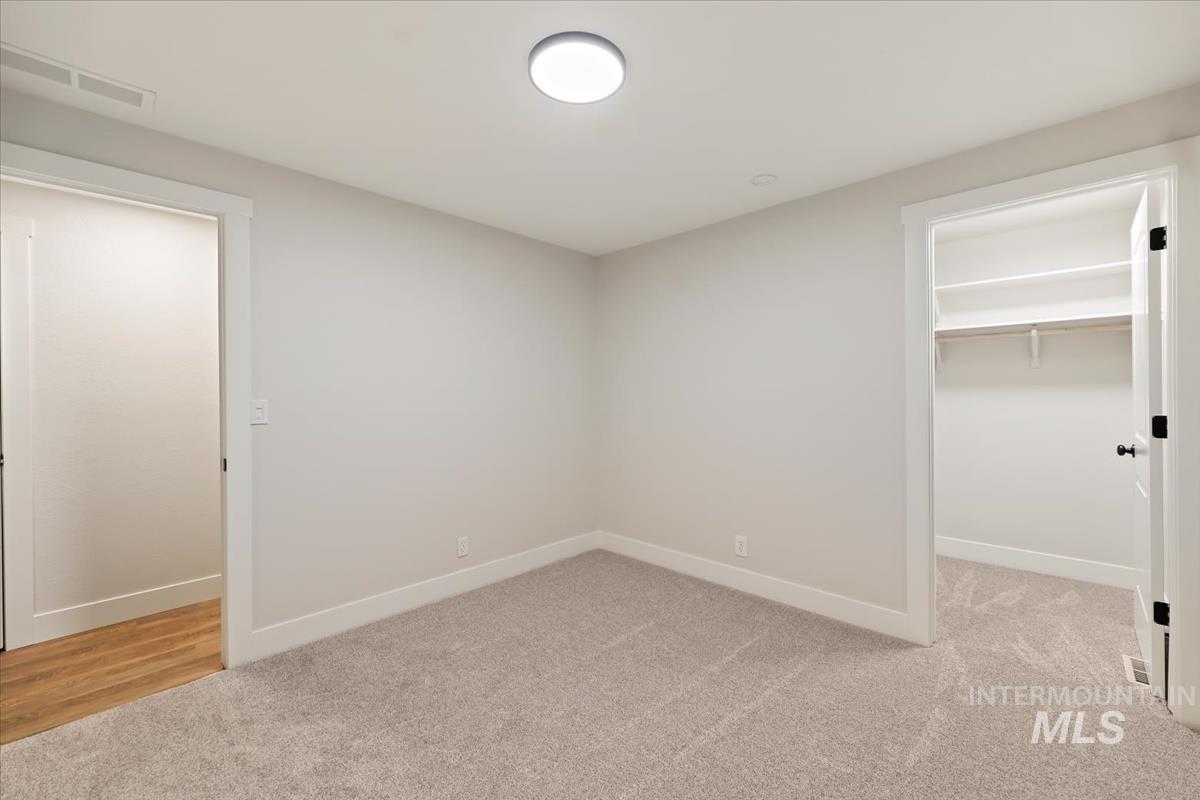 Unfurnished bedroom featuring light carpet and a spacious closet