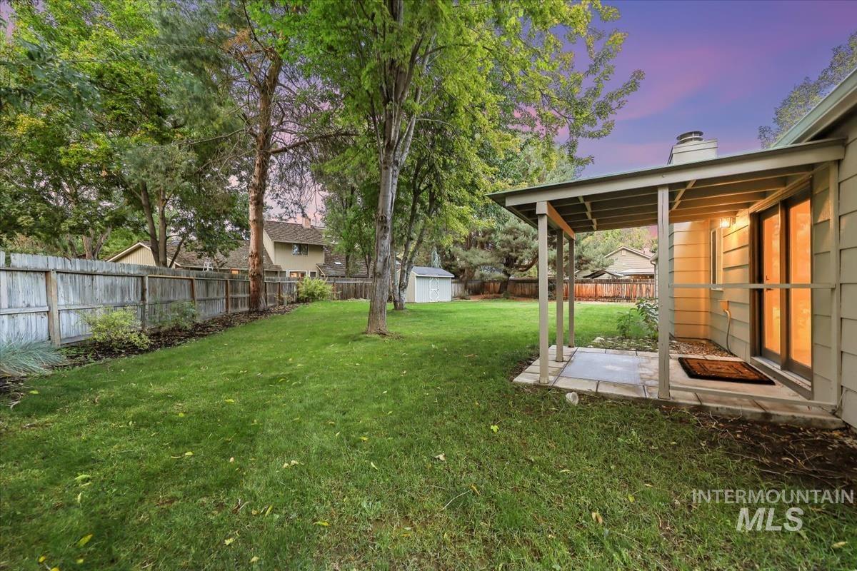 Fenced backyard with a patio and a storage unit