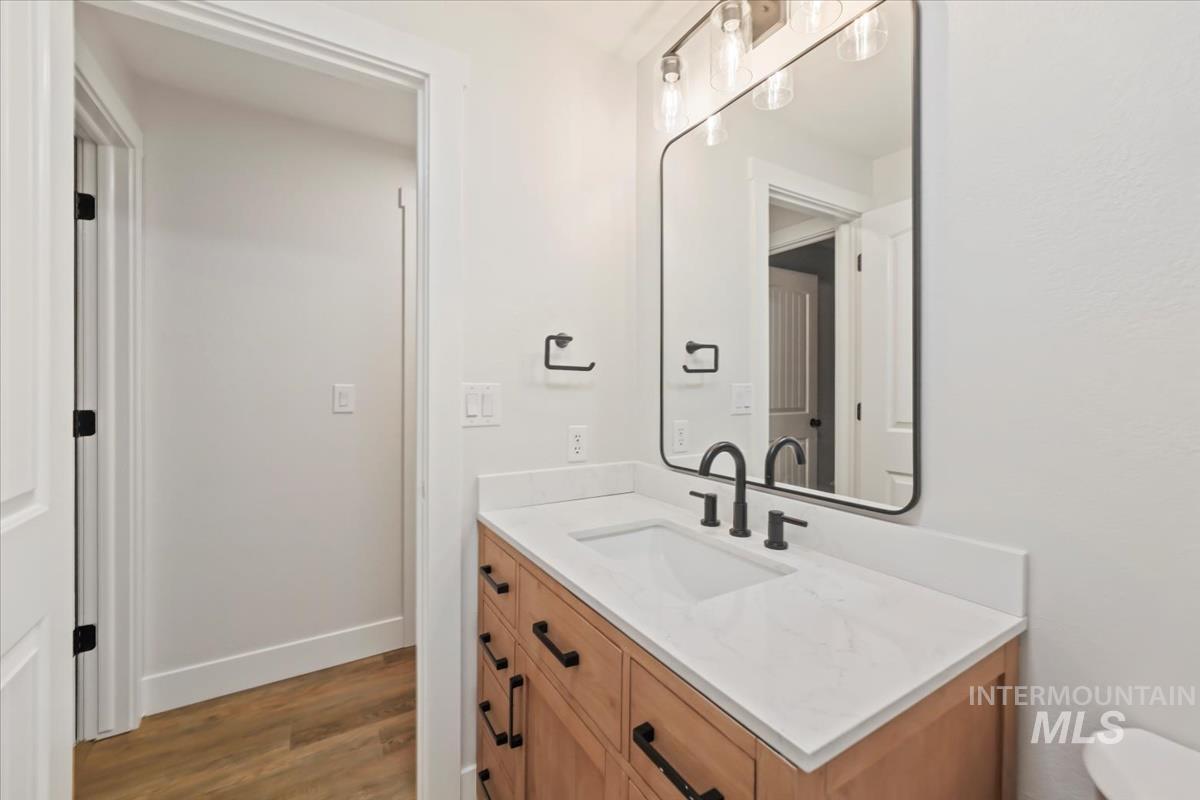 Half bathroom featuring vanity and dark wood-type flooring