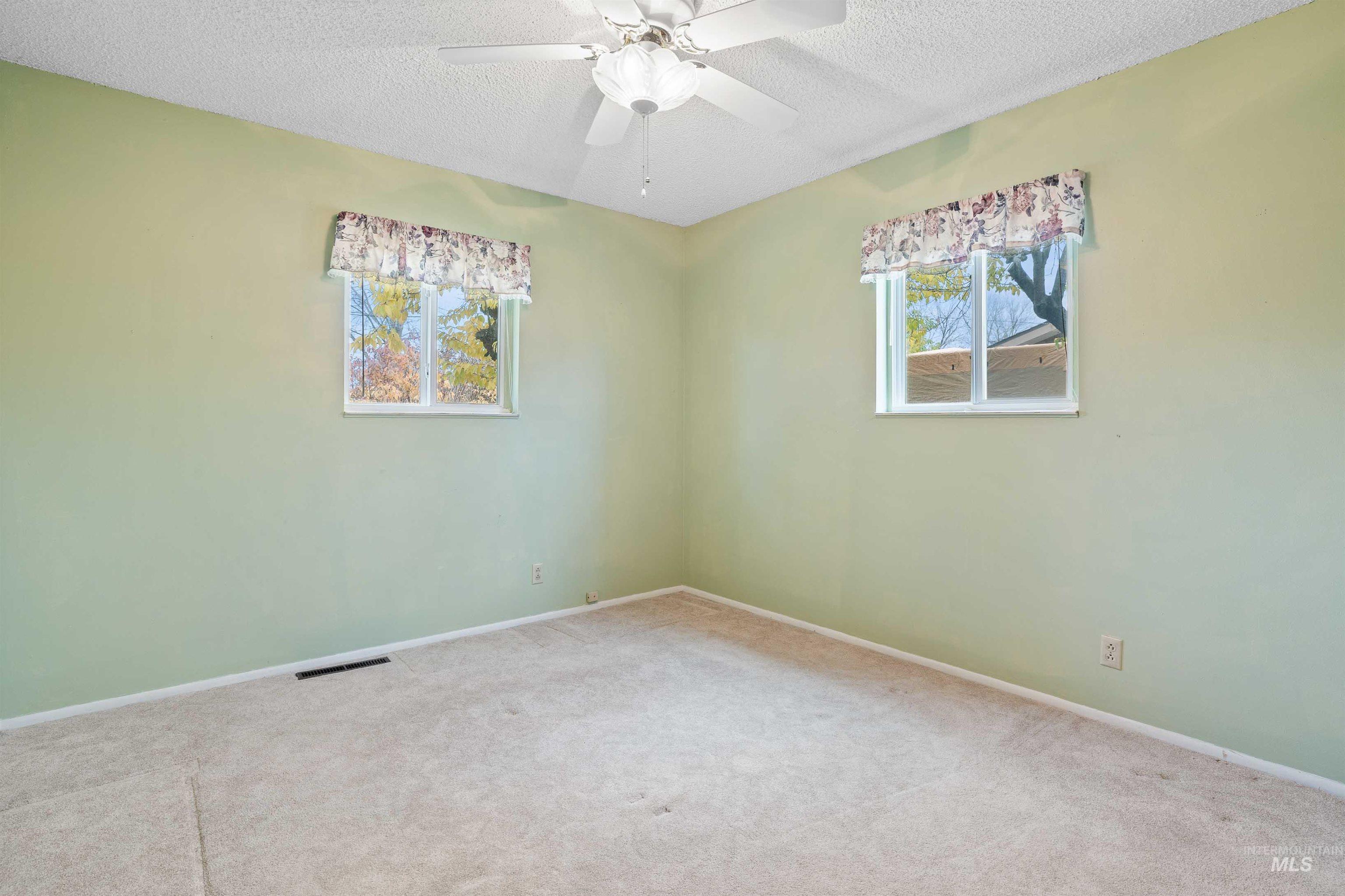 Carpeted empty room with a textured ceiling and ceiling fan