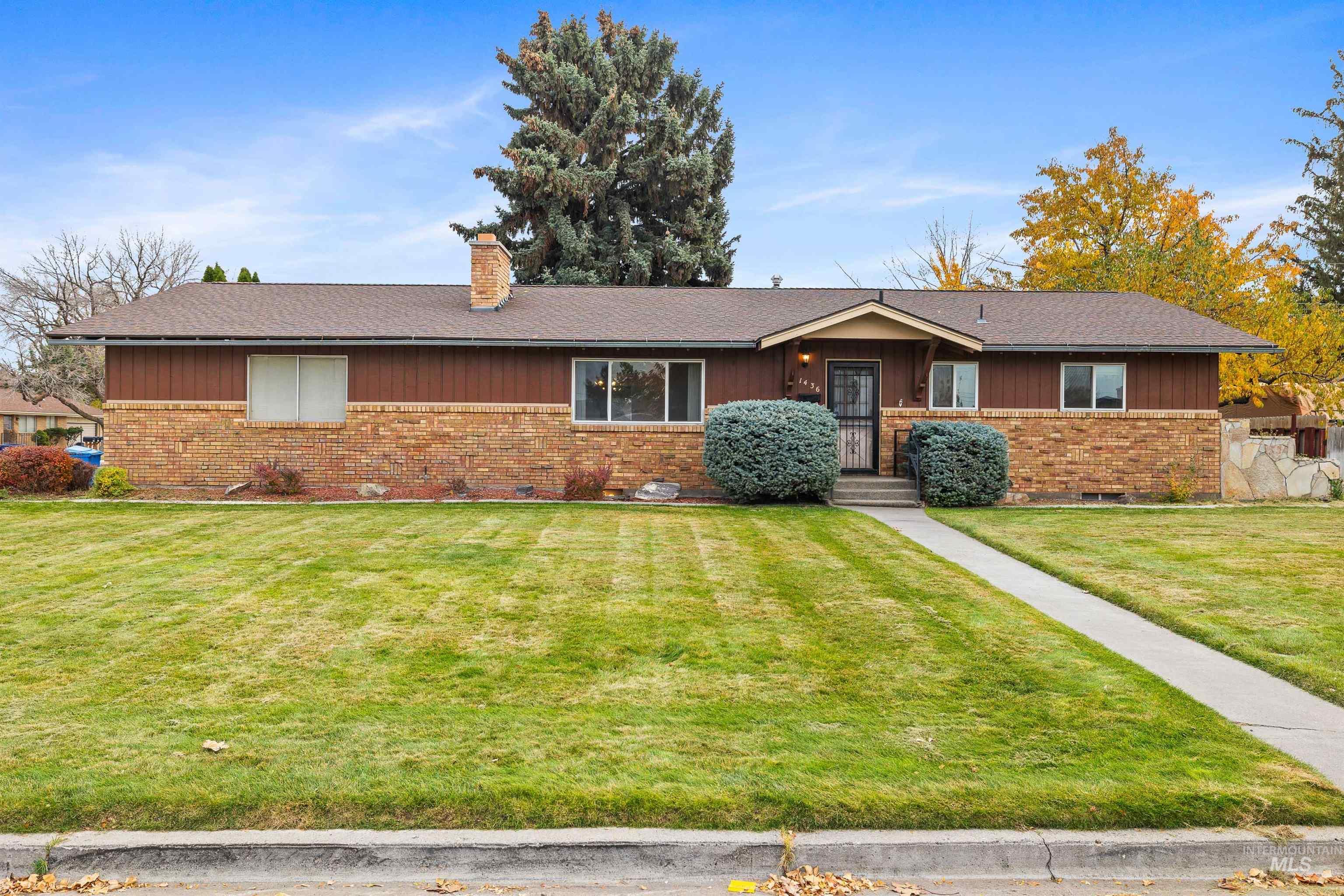 Ranch-style home with brick siding, a front lawn, and a chimney