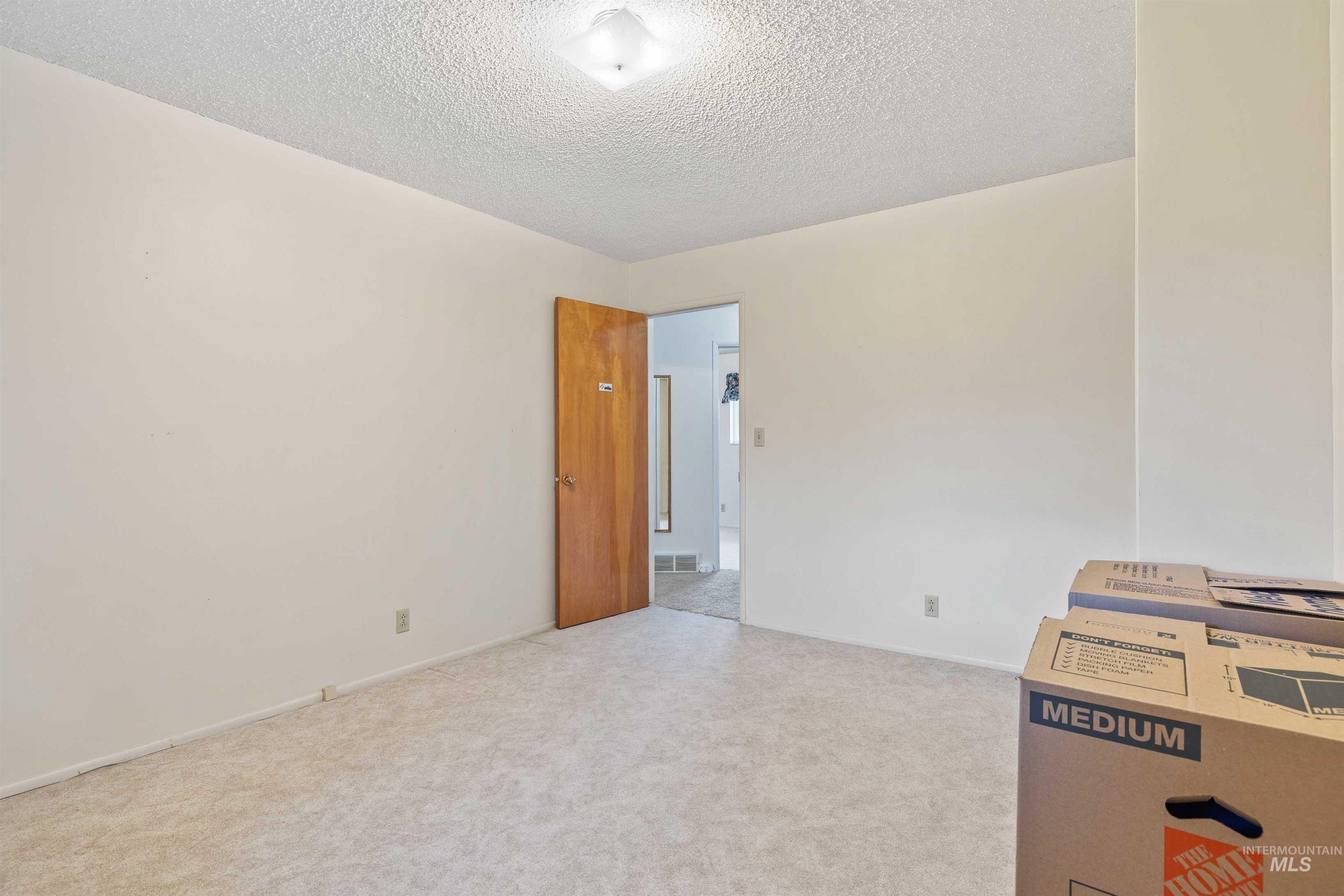 Spare room featuring light carpet and a textured ceiling