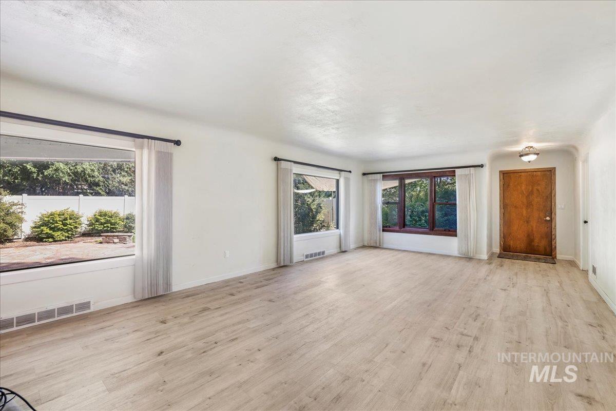 Unfurnished living room featuring light wood-style flooring and baseboards