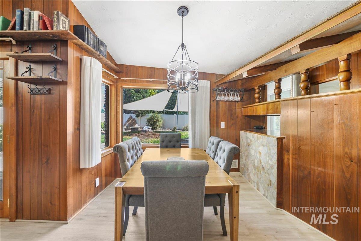 Dining space featuring wood walls, a chandelier, and light wood-style floors