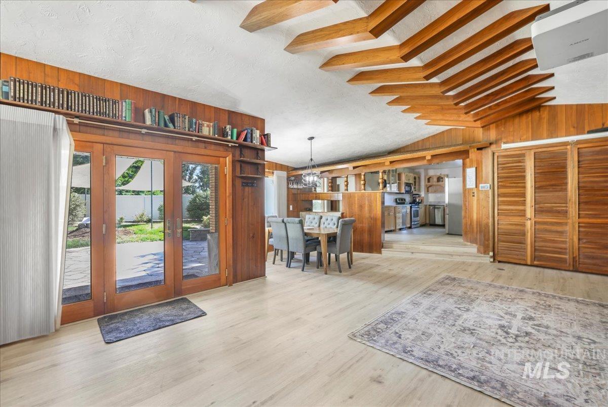 Foyer with wooden walls, lofted ceiling, french doors, wood finished floors, and a chandelier