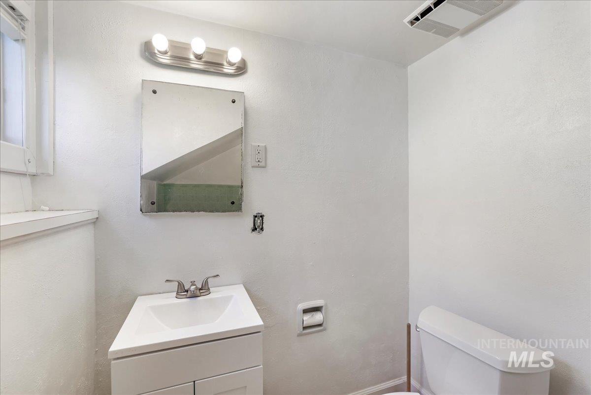 Half bathroom with vanity and a textured wall