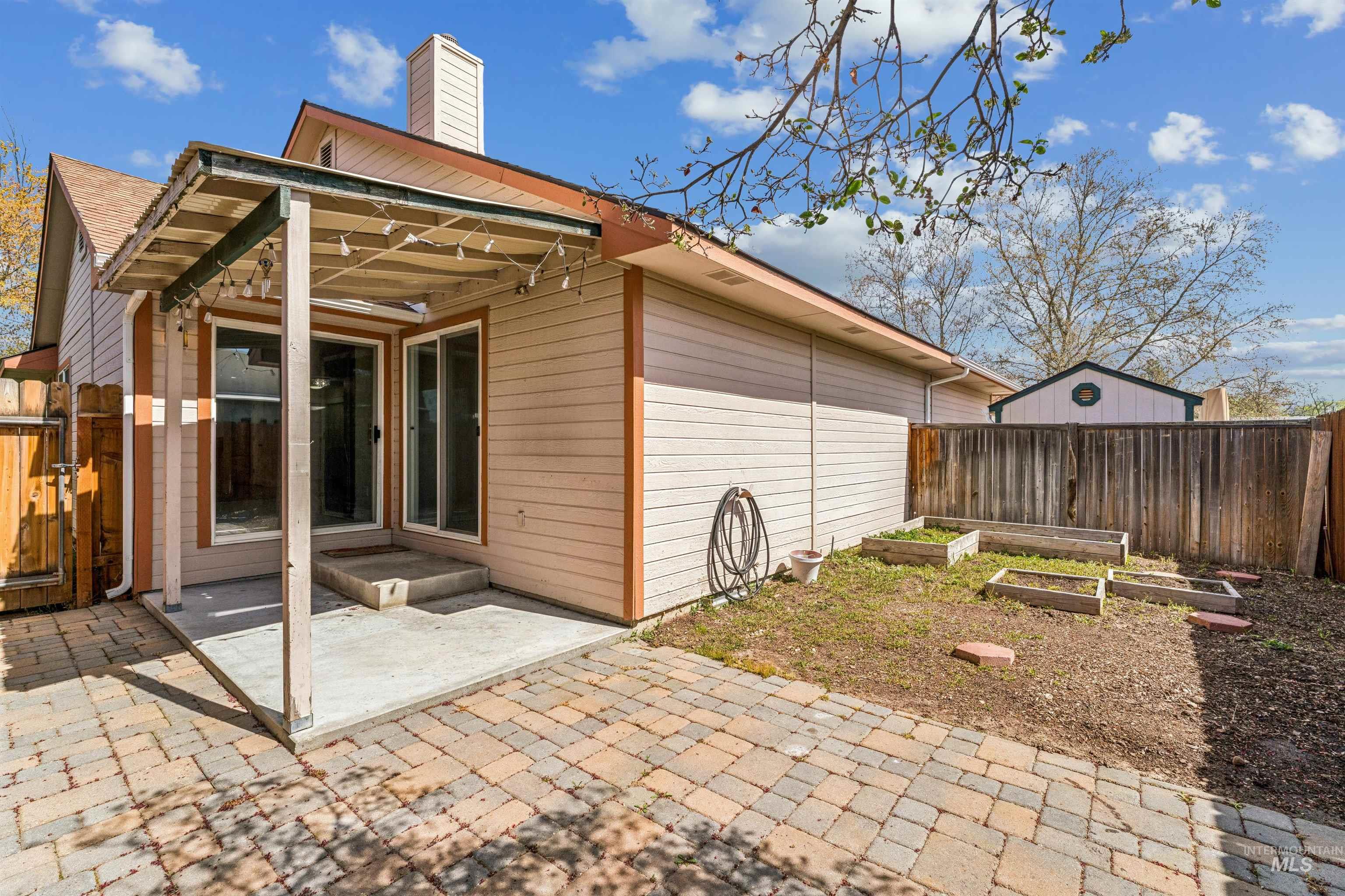 Rear view of property with a vegetable garden, a patio area, a fenced backyard, and a chimney