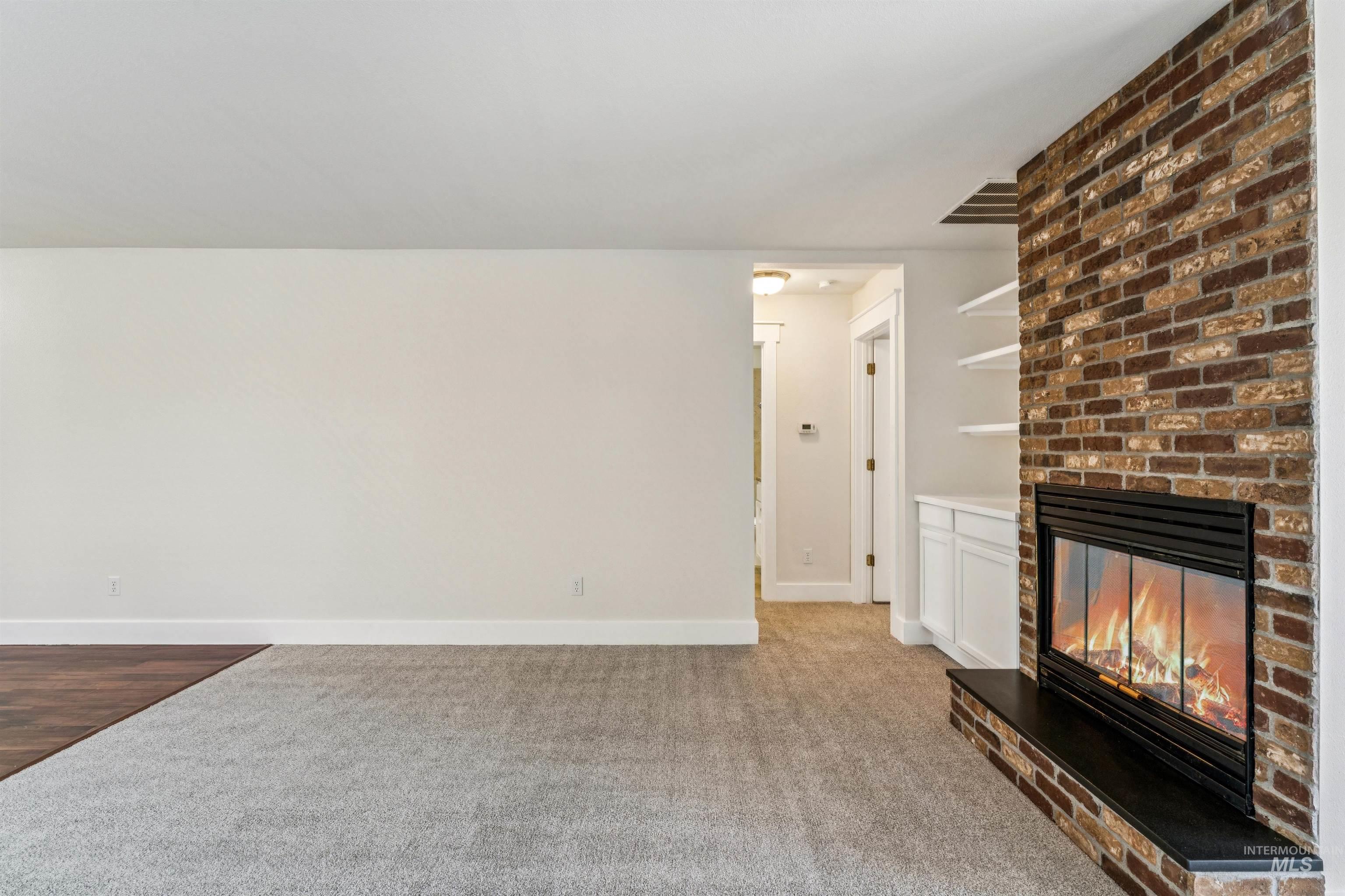 Unfurnished living room with a fireplace and light colored carpet