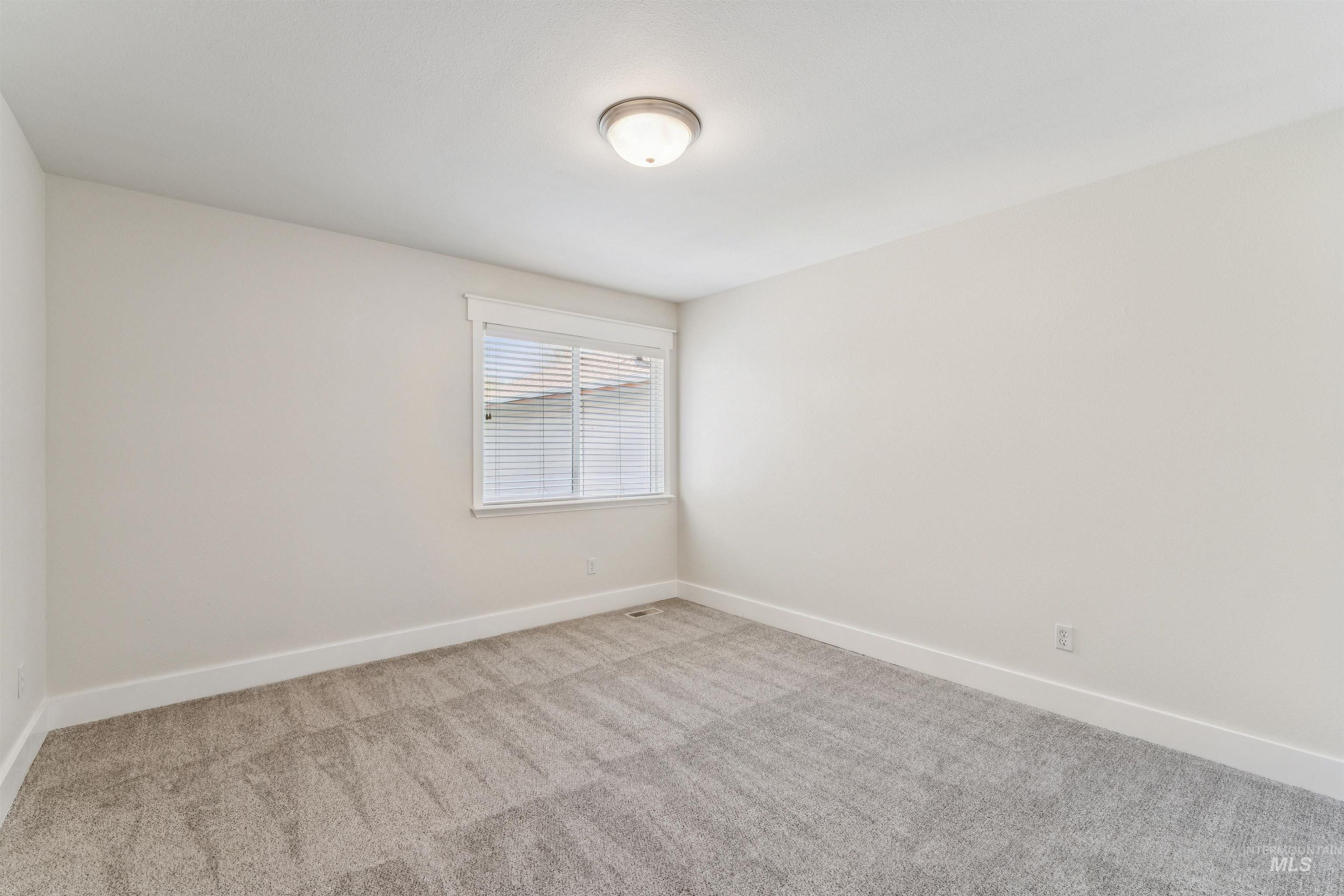 Spare room featuring baseboards and light colored carpet