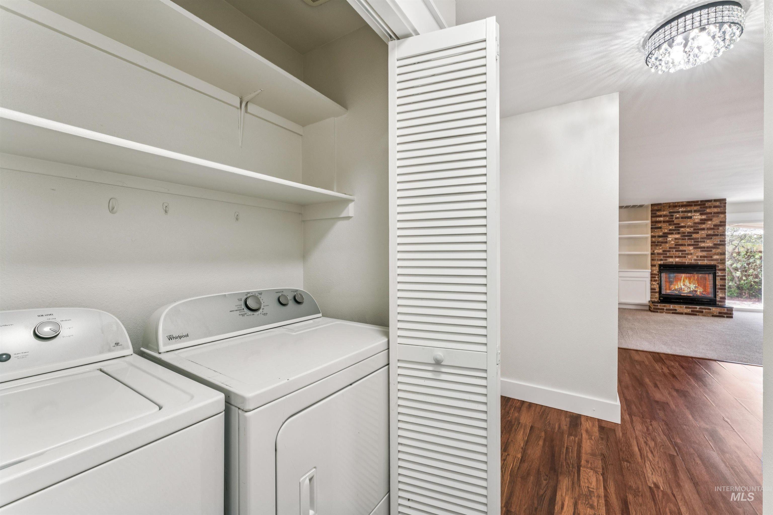 Laundry area with dark wood-style flooring, independent washer and dryer, and a fireplace