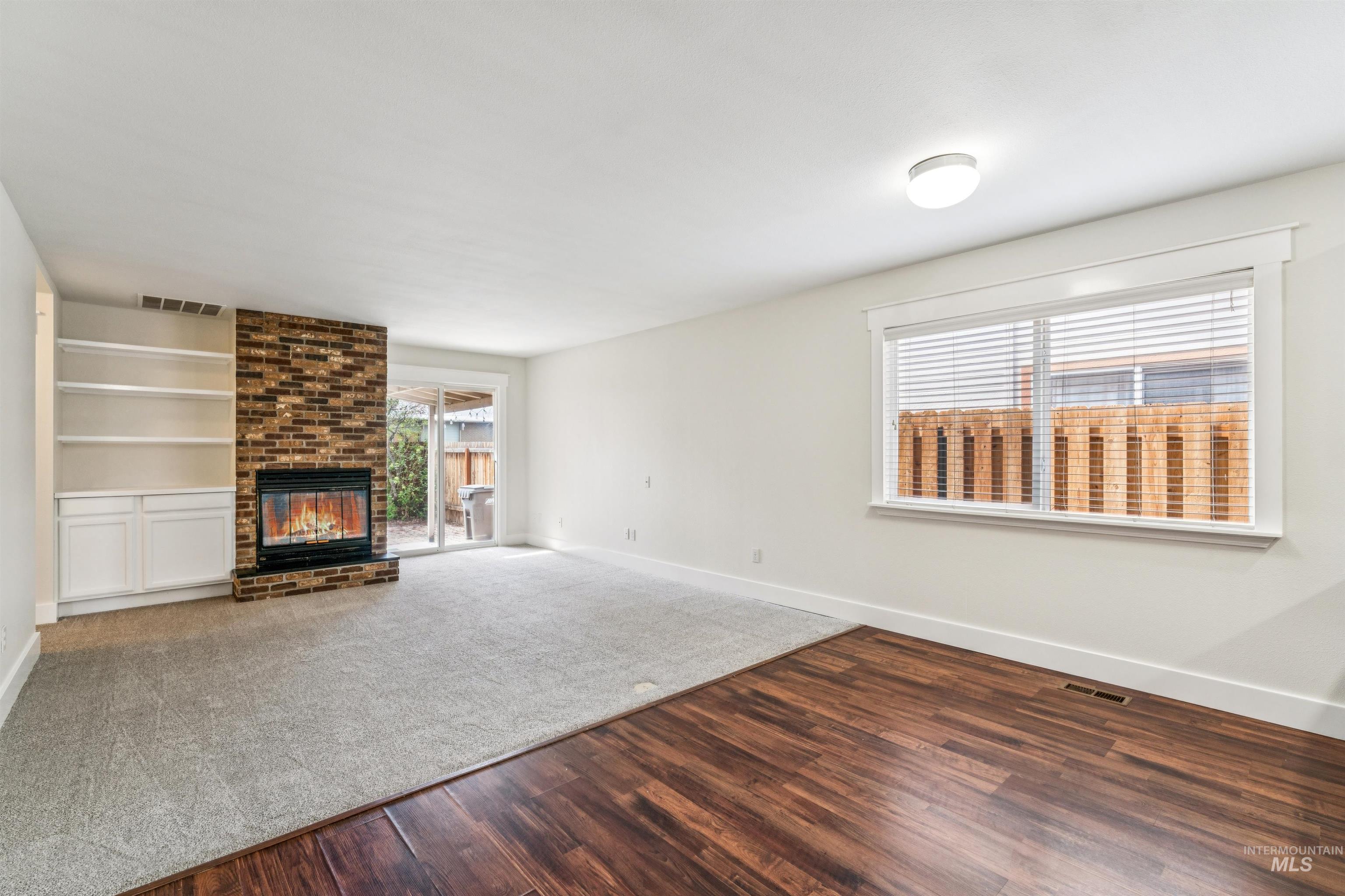 Unfurnished living room with dark wood-style flooring, a fireplace, and dark colored carpet