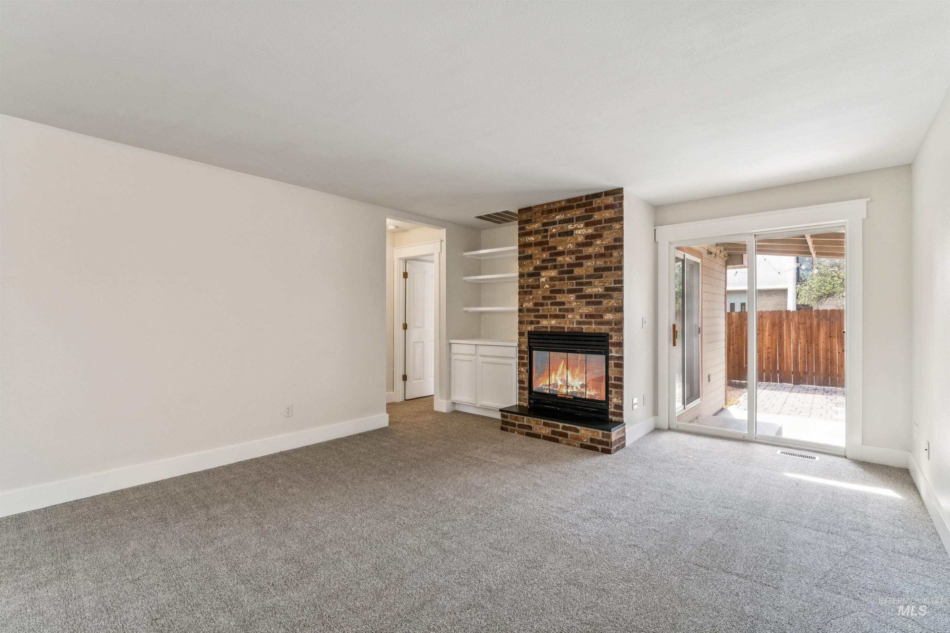 Unfurnished living room with a fireplace, built in features, and carpet