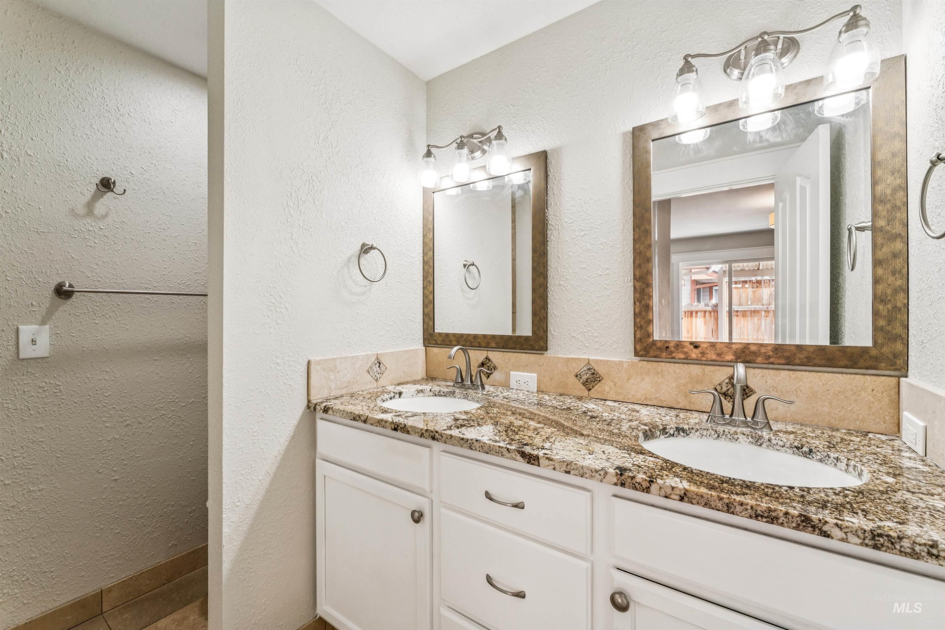 Bathroom featuring a textured wall and double vanity