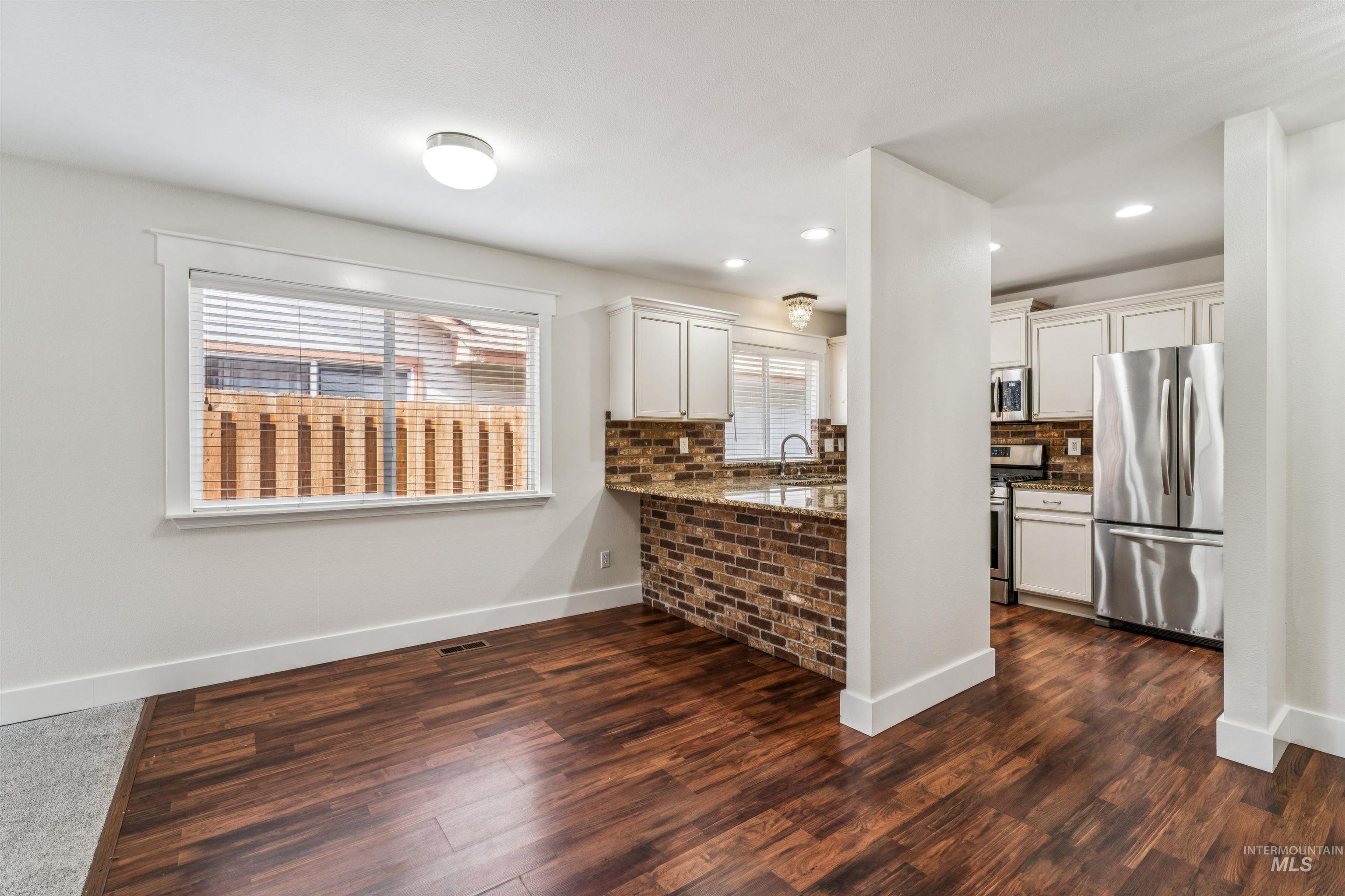 Kitchen with dark stone counters, stainless steel appliances, dark wood-style floors, white cabinets, and recessed lighting