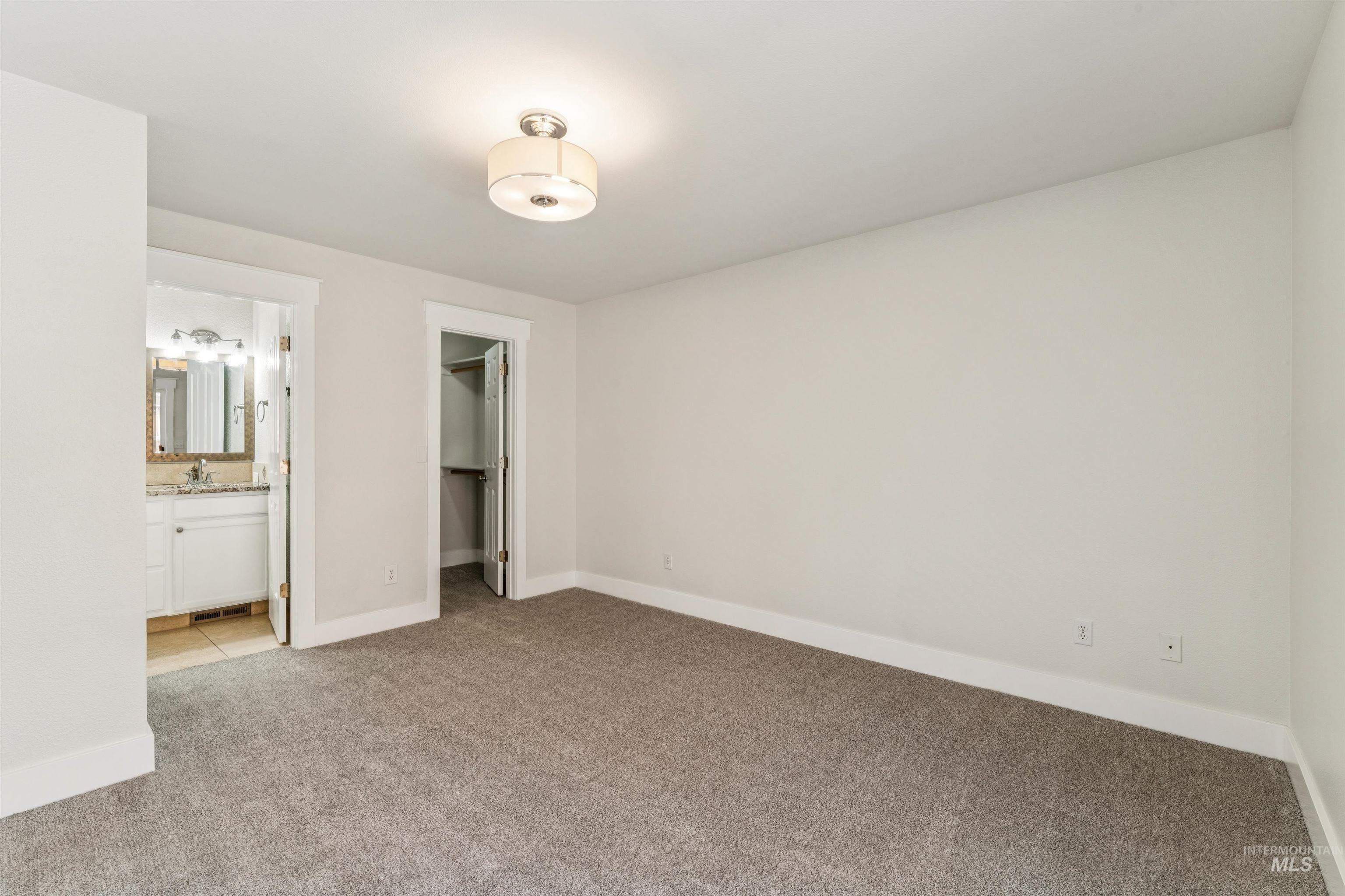 Unfurnished bedroom with a walk in closet and light colored carpet