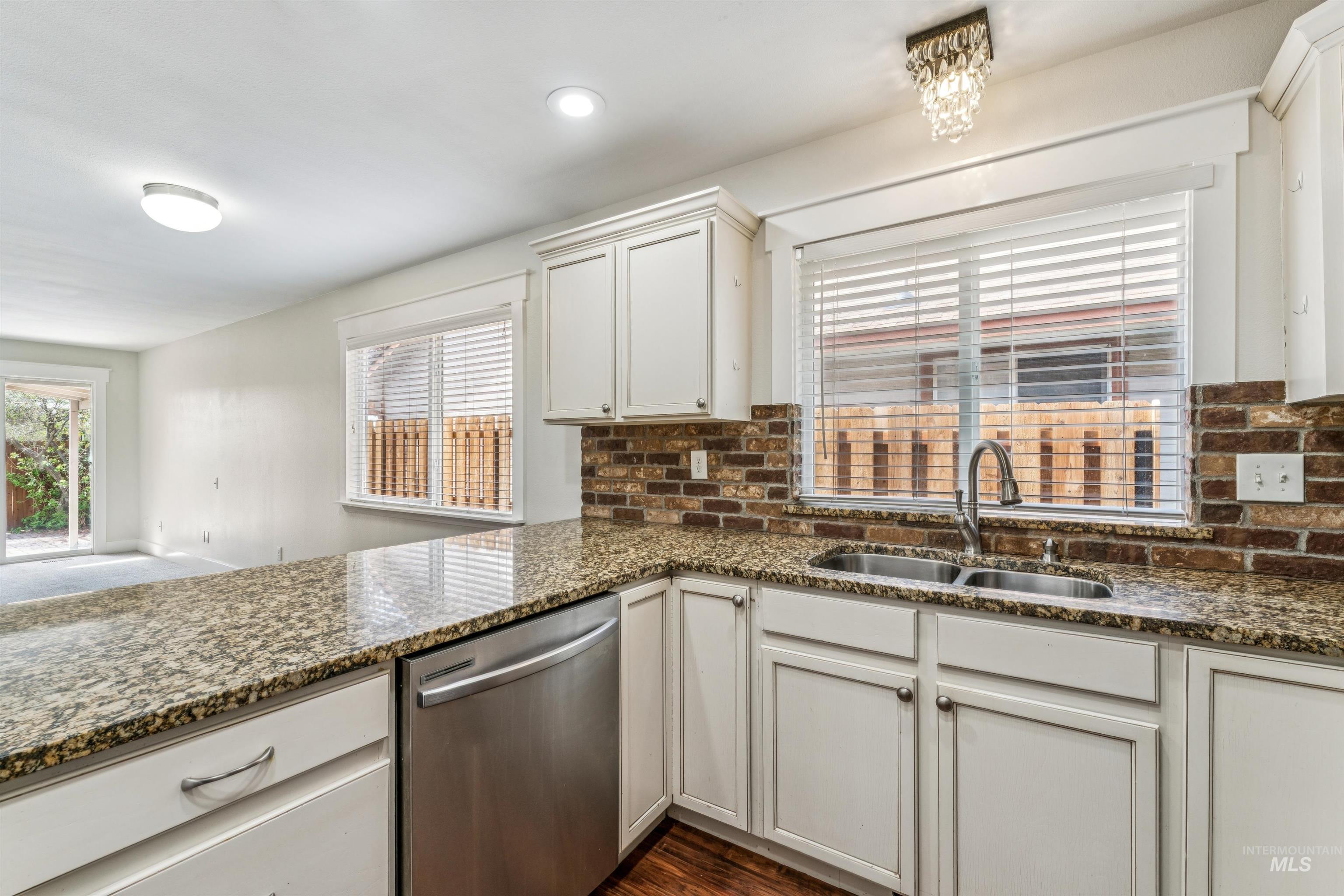 Kitchen with stainless steel dishwasher, dark stone counters, white cabinetry, plenty of natural light, and recessed lighting